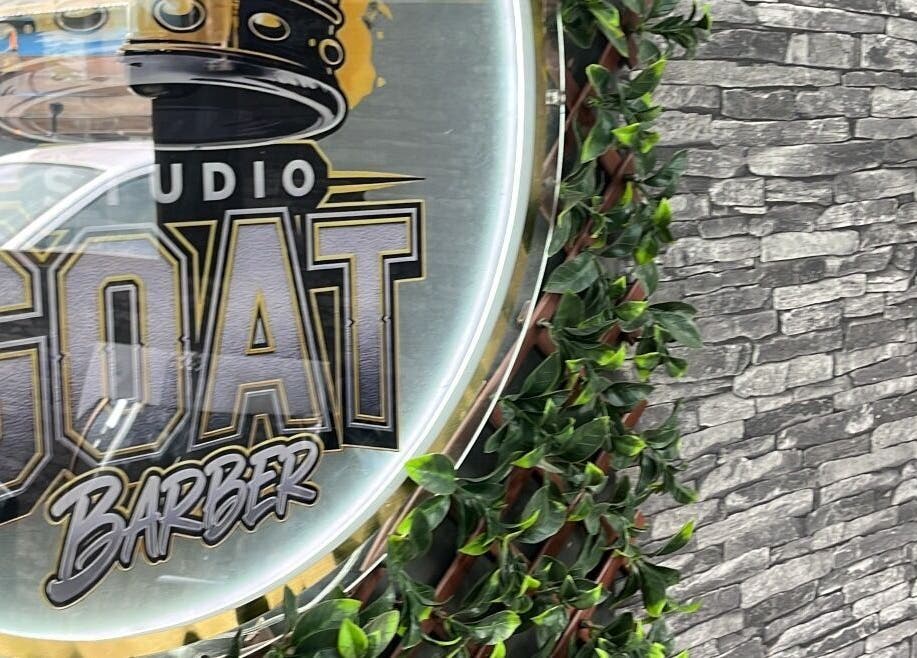 Enseigne de Studio goat barber sur mur en pierre et feuillage à Papeete, Îles Du Vent, PF.