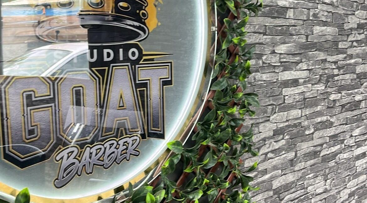 Enseigne de Studio goat barber sur mur en pierre et feuillage à Papeete, Îles Du Vent, PF.