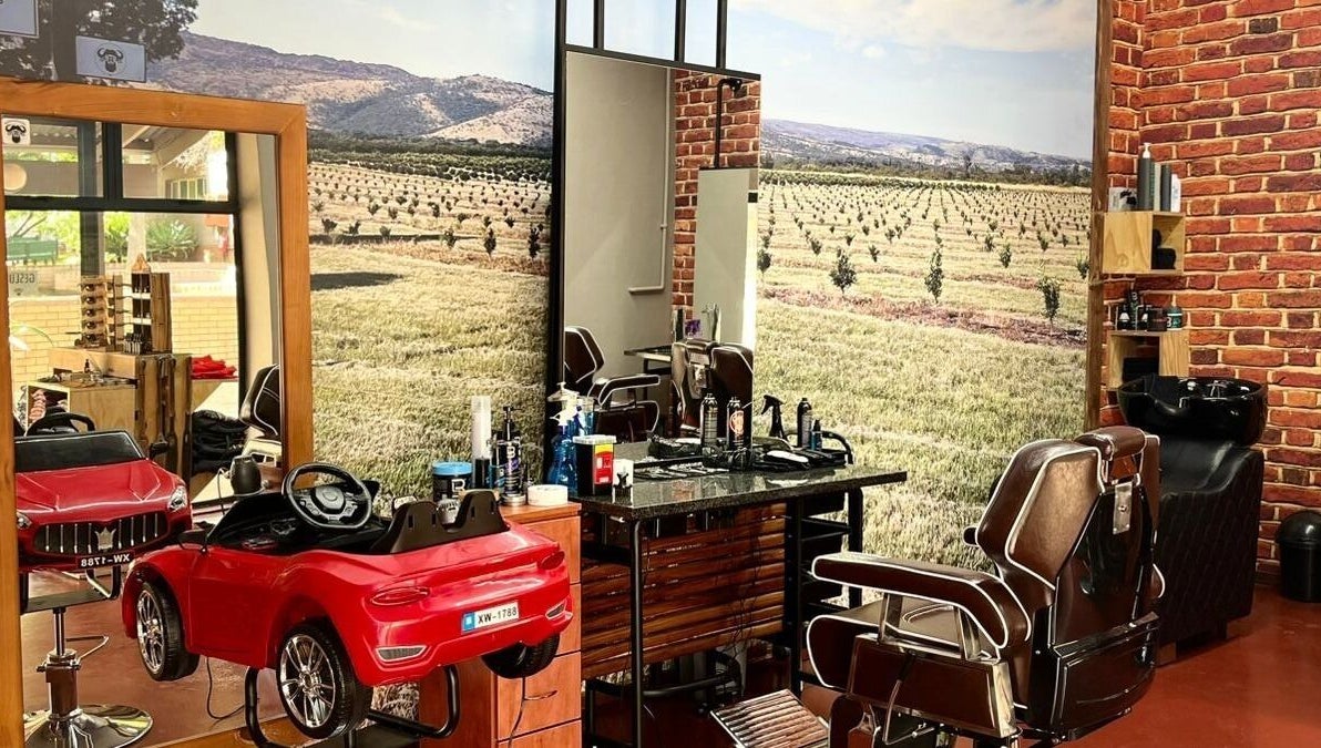 Buffelsfontein Barbier Menlo Park interior in Pretoria, Gauteng showcasing vintage barber chairs and brick walls.