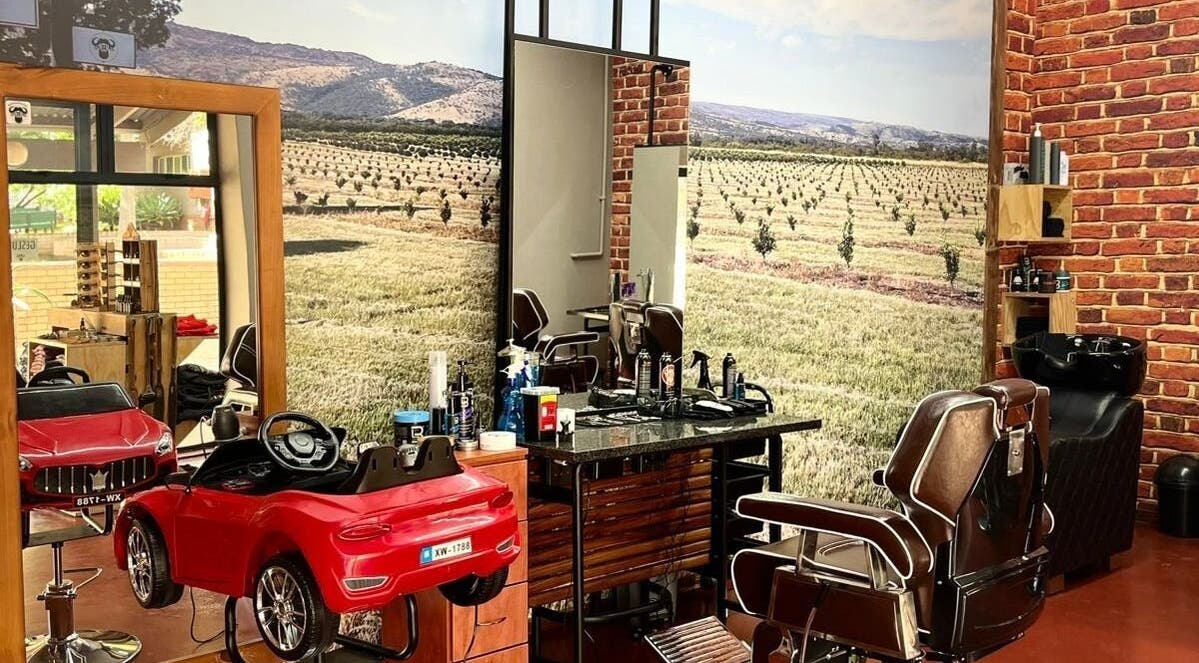 Buffelsfontein Barbier Menlo Park interior in Pretoria, Gauteng showcasing vintage barber chairs and brick walls.