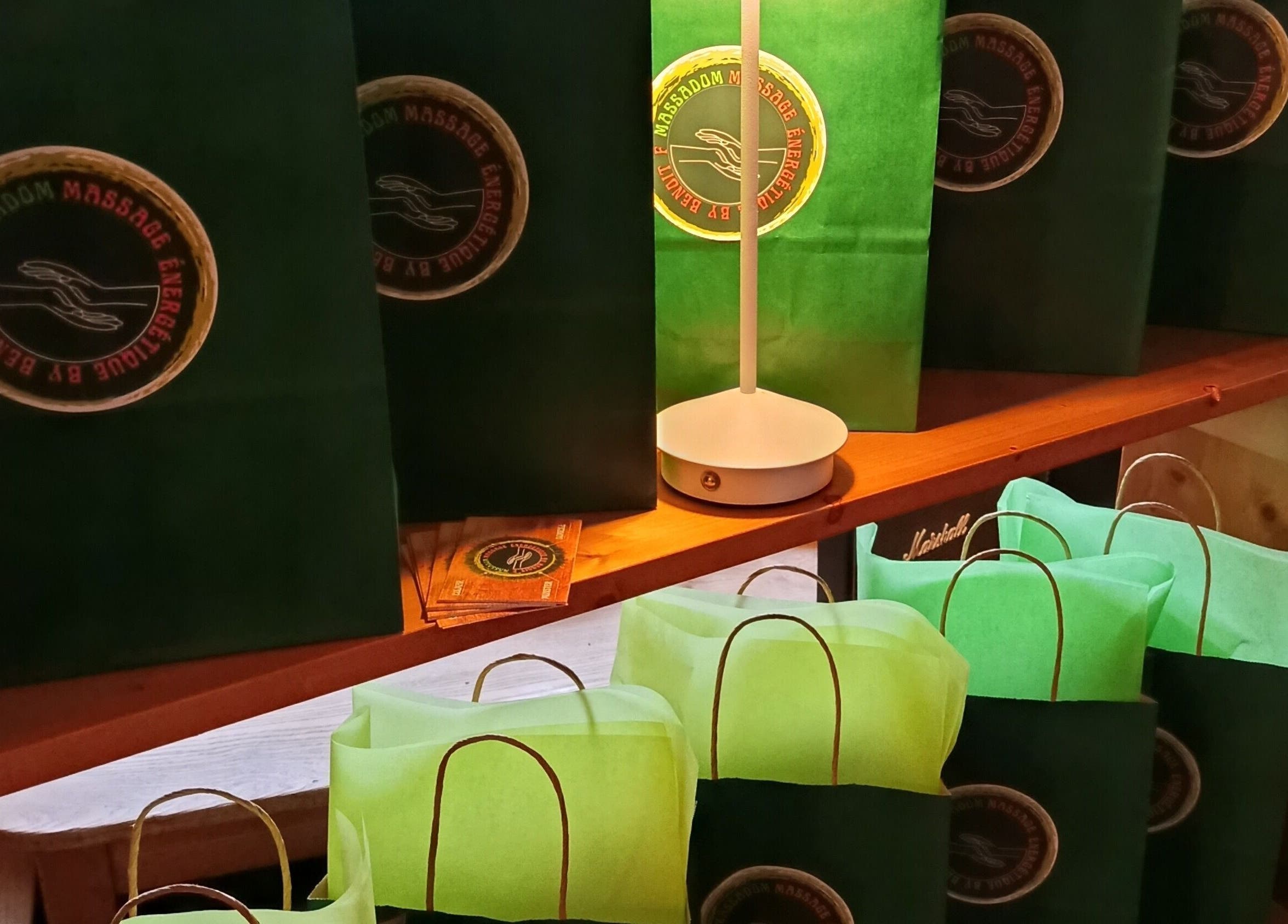 Sacs cadeaux verts avec logo de Massa Dom à Colmar, Grand Est, FR, sur une étagère en bois.