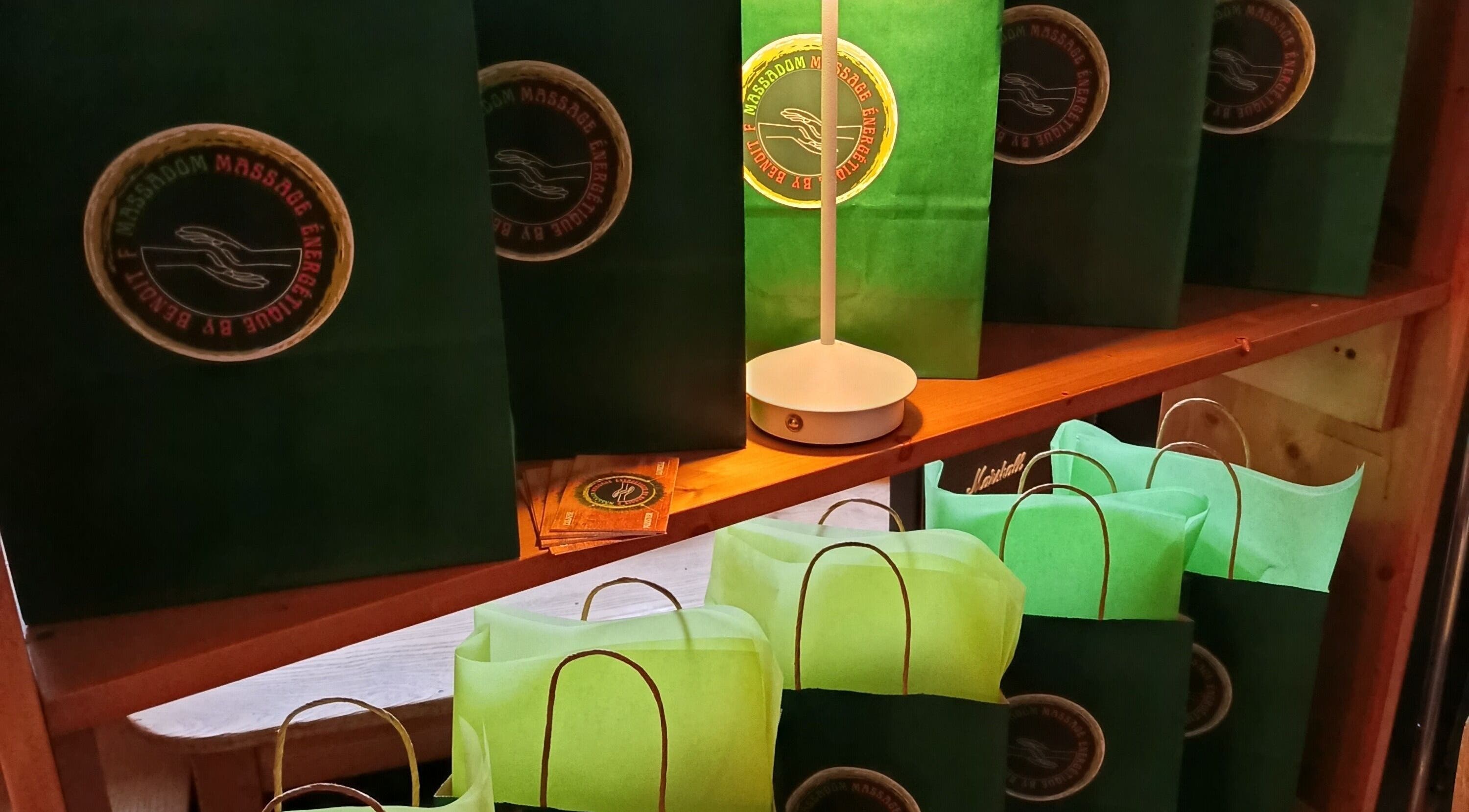 Sacs cadeaux verts avec logo de Massa Dom à Colmar, Grand Est, FR, sur une étagère en bois.