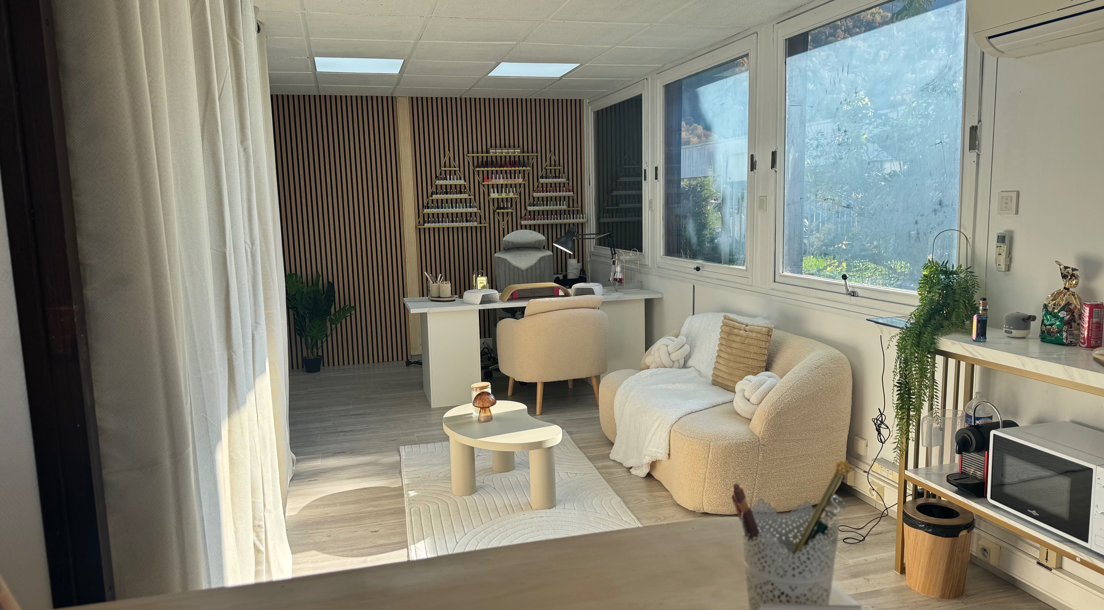 Intérieur chic de Happy Nail's à Domène, Auvergne-rhône-alpes, FR avec un canapé élégant et une table moderne.