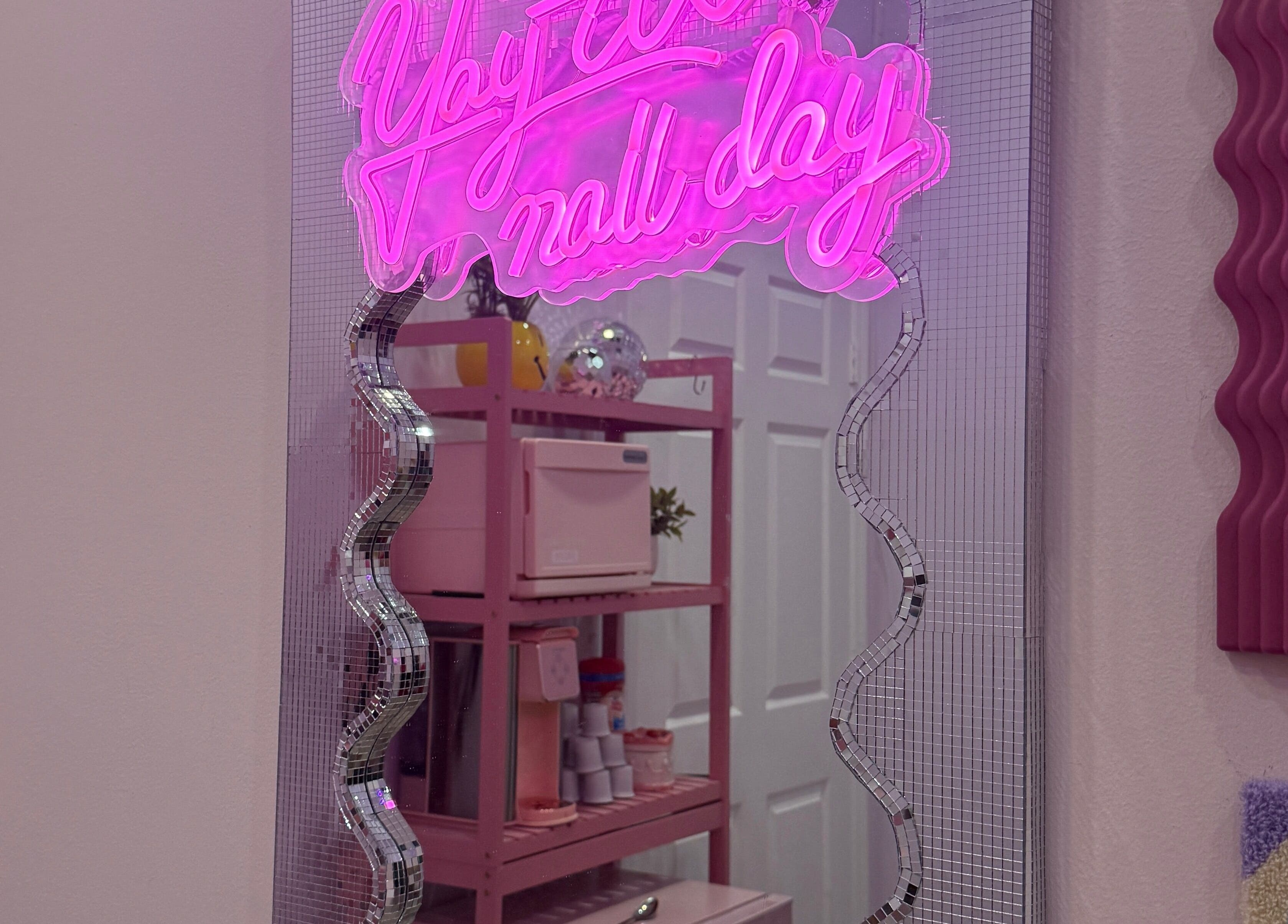 Neon pink mirror sign at The Nail Room, Hialeah, Florida, US highlights chic decor and ambiance.