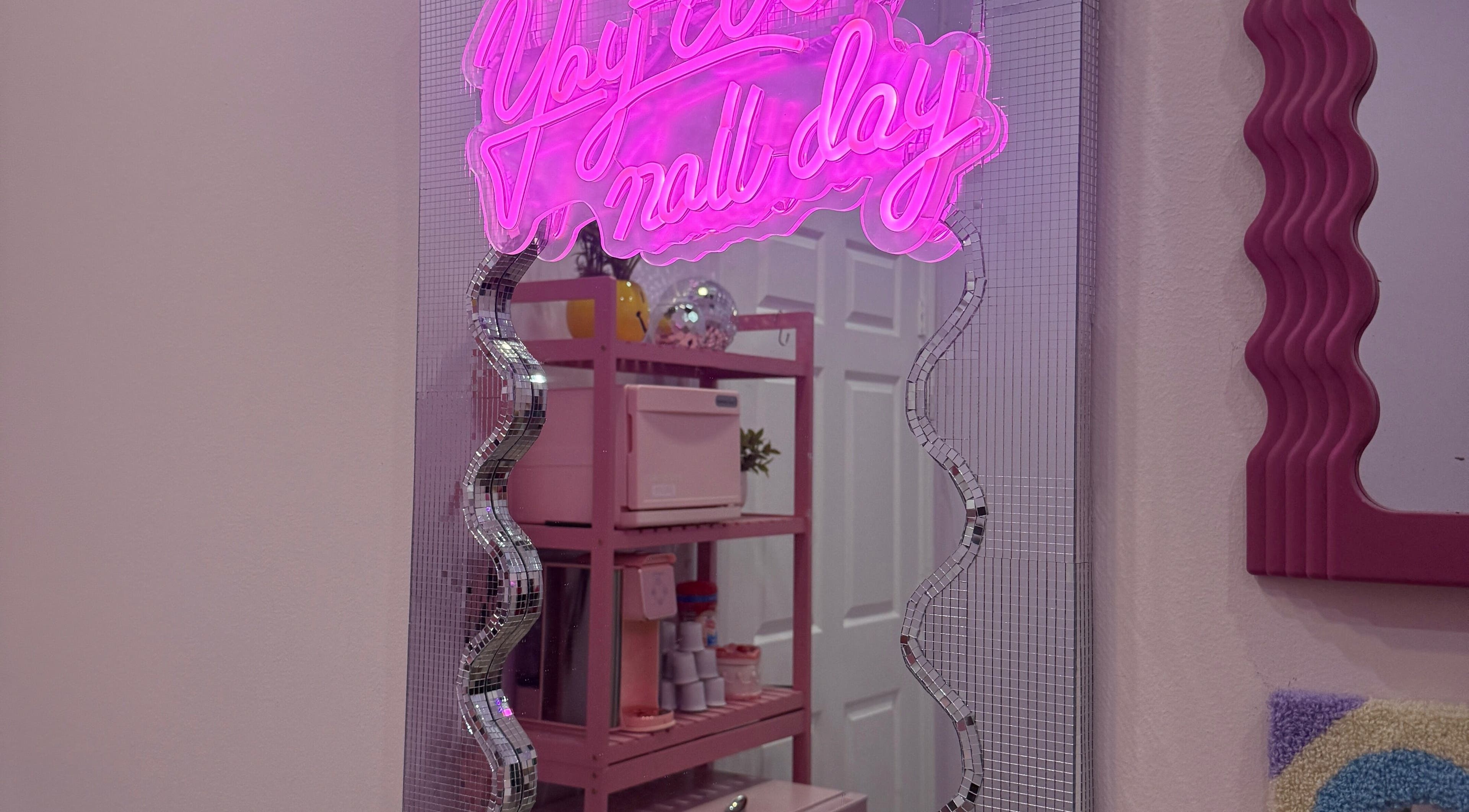 Neon pink mirror sign at The Nail Room, Hialeah, Florida, US highlights chic decor and ambiance.