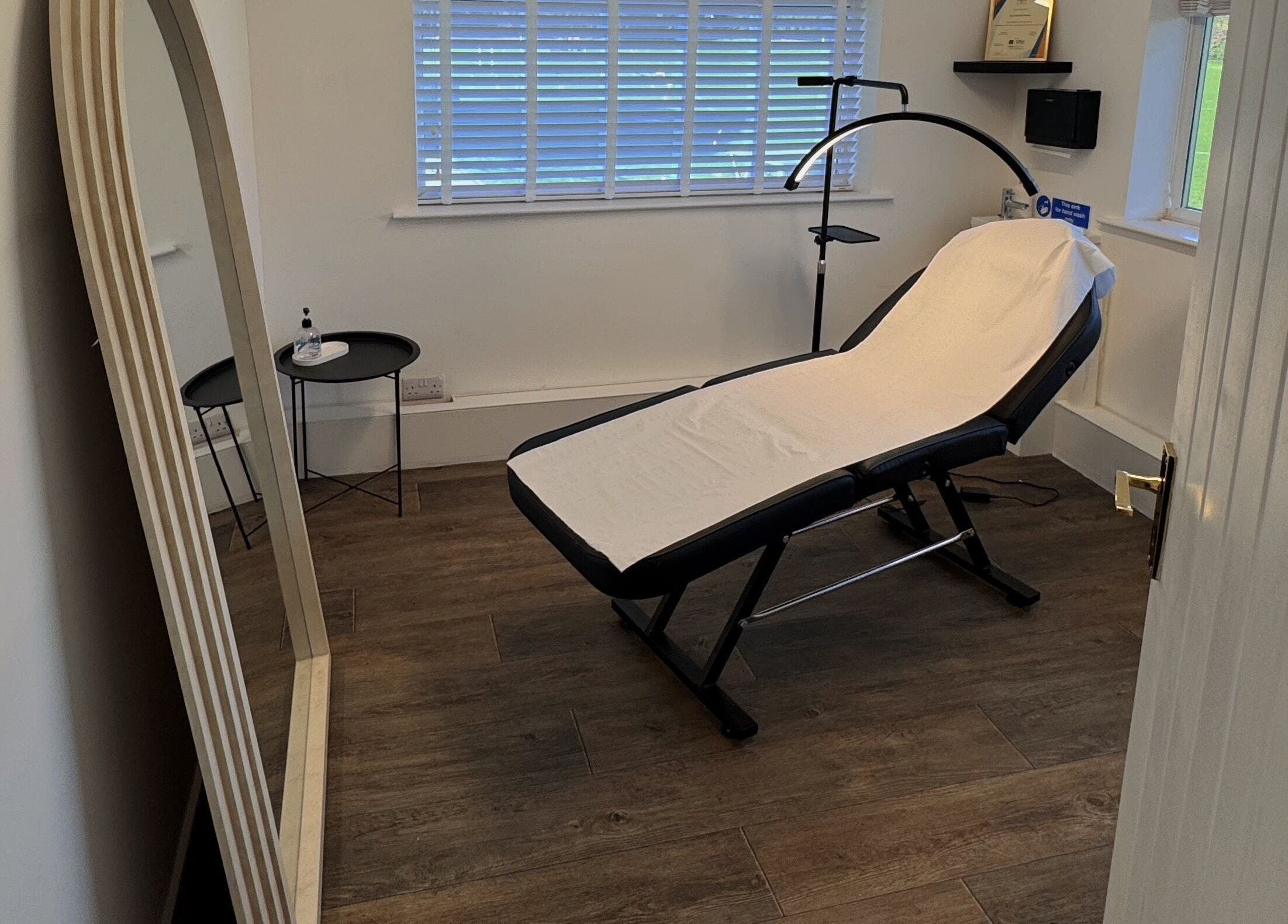 Serene treatment room at Reve Wellness Clinic in Peterborough, England, GB with a therapy bed and large mirror.