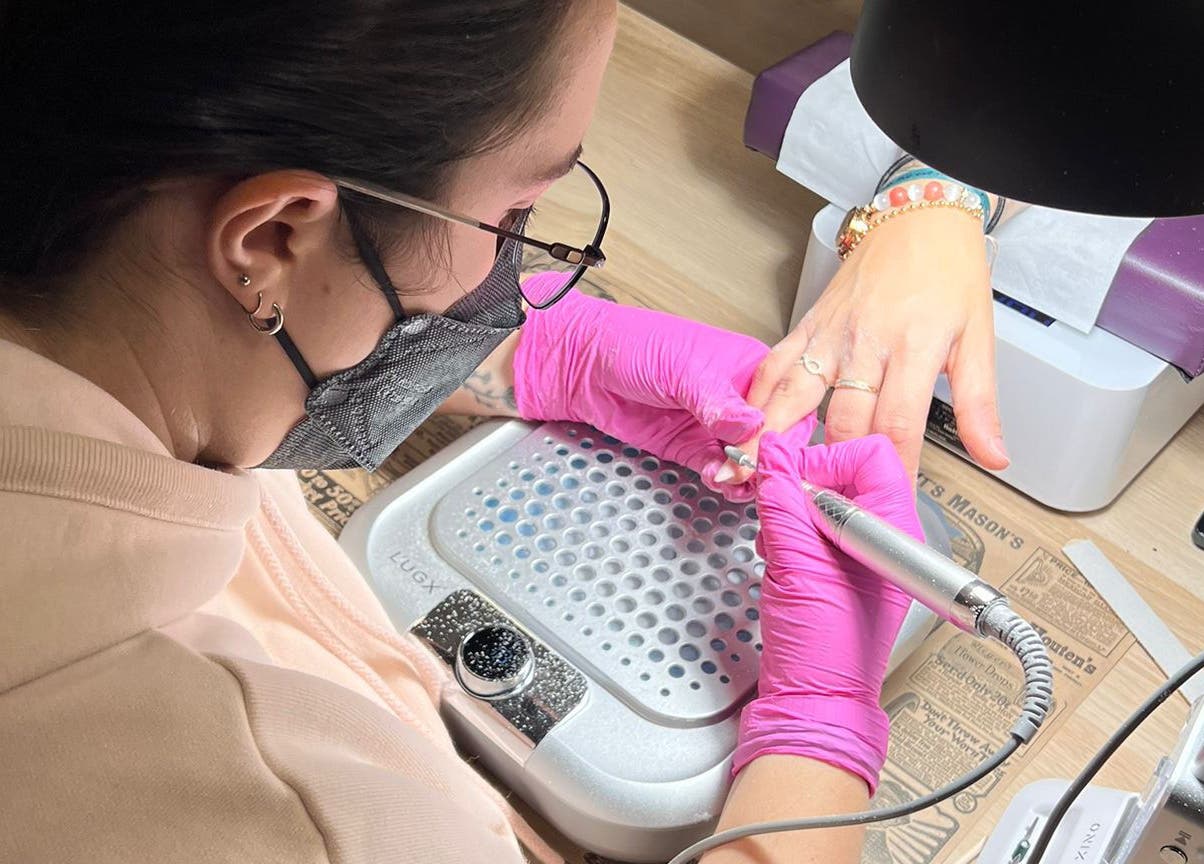 Soin manucure professionnel chez Poppynails à Saint Yvi, FR, avec des gants roses et outils spécialisés.