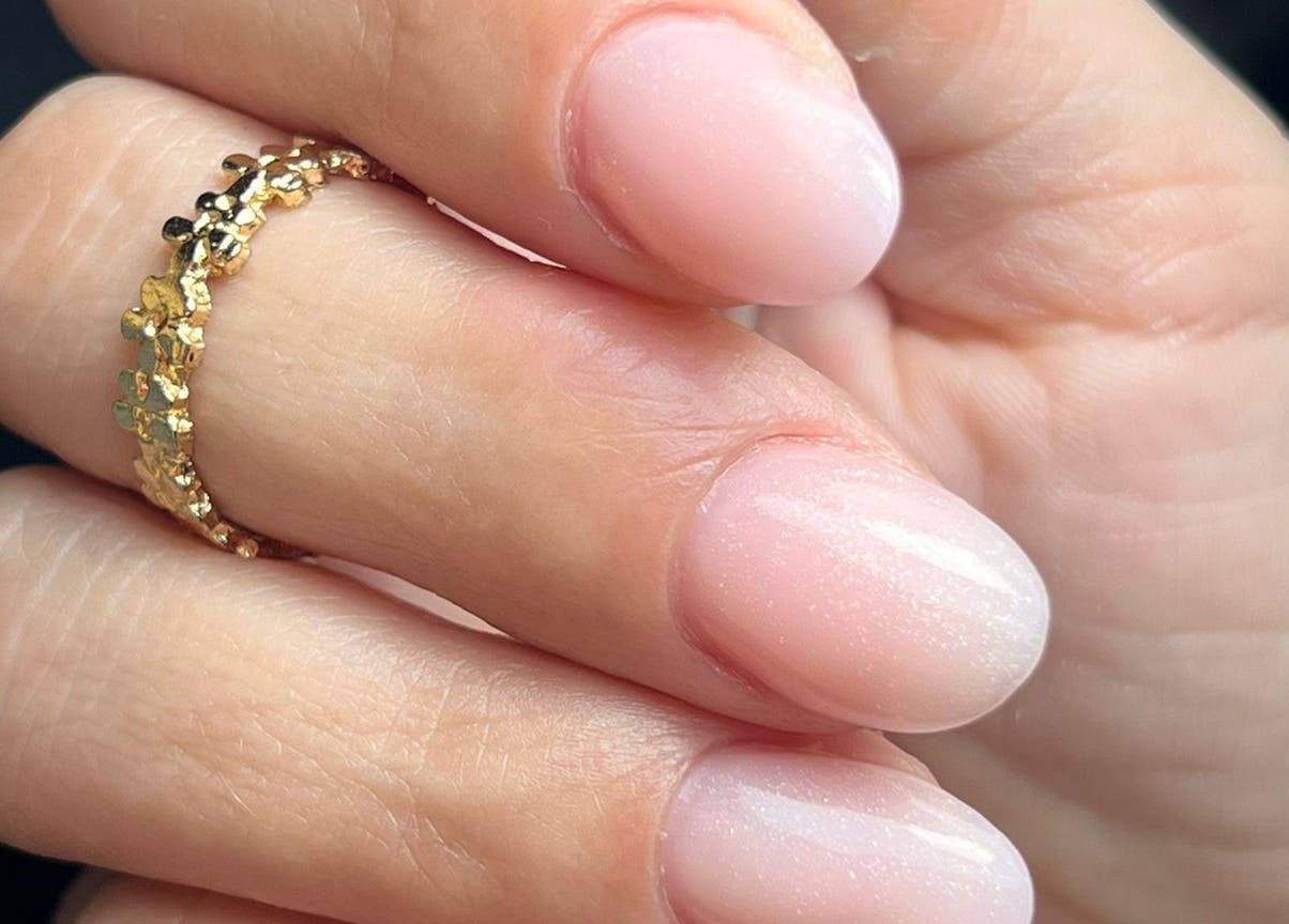 Manucure étincelante chez Poppynails à Saint Yvi, FR. Ongles brillants avec une bague dorée.