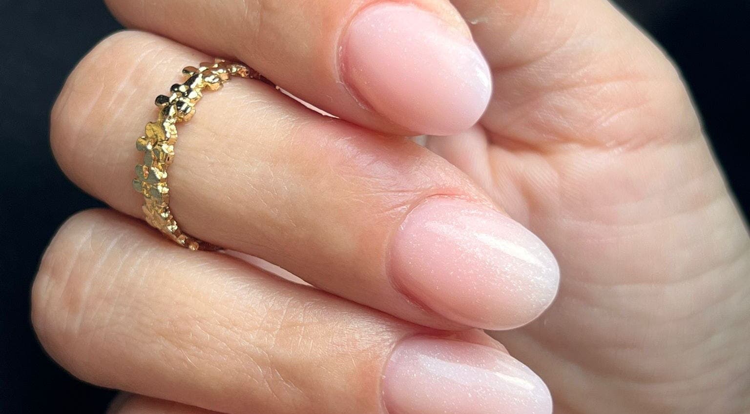 Manucure étincelante chez Poppynails à Saint Yvi, FR. Ongles brillants avec une bague dorée.