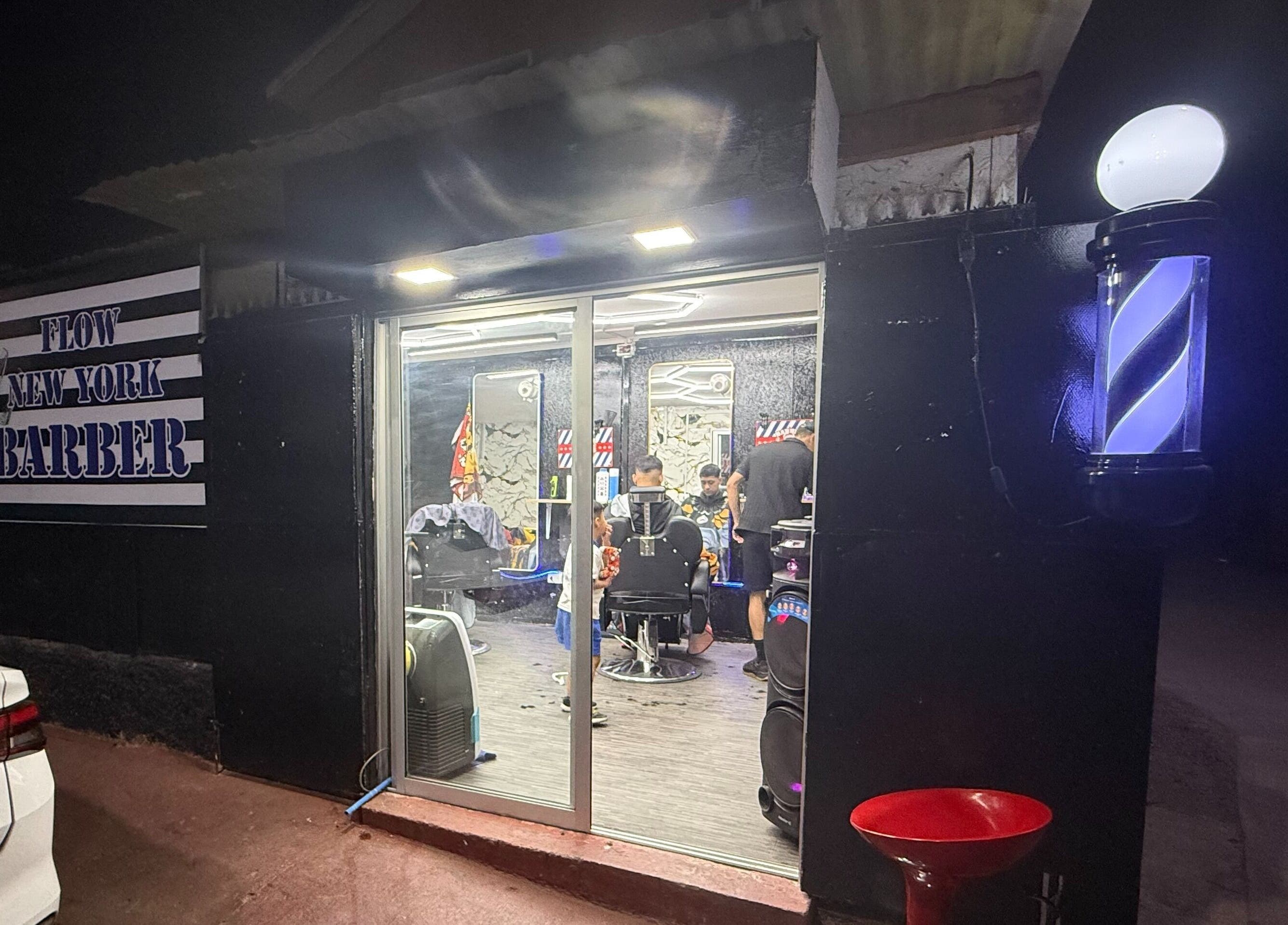 Flow newyork barber at night in Colina, Región Metropolitana, CL, warmly lit with barbers inside.