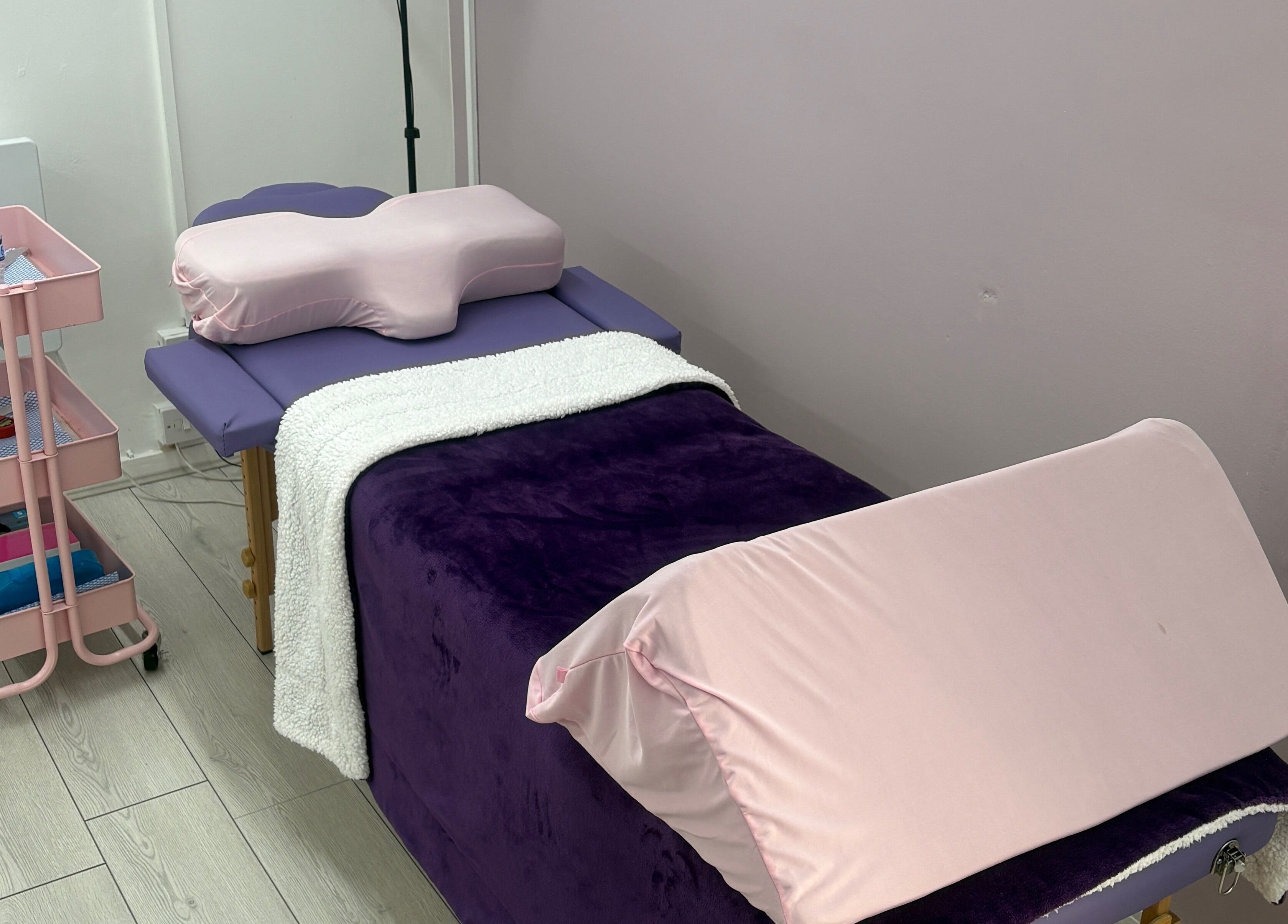 Treatment bed at Emerge Beauty Studio, Hollywood, England, GB, featuring plush purple and pink decor.