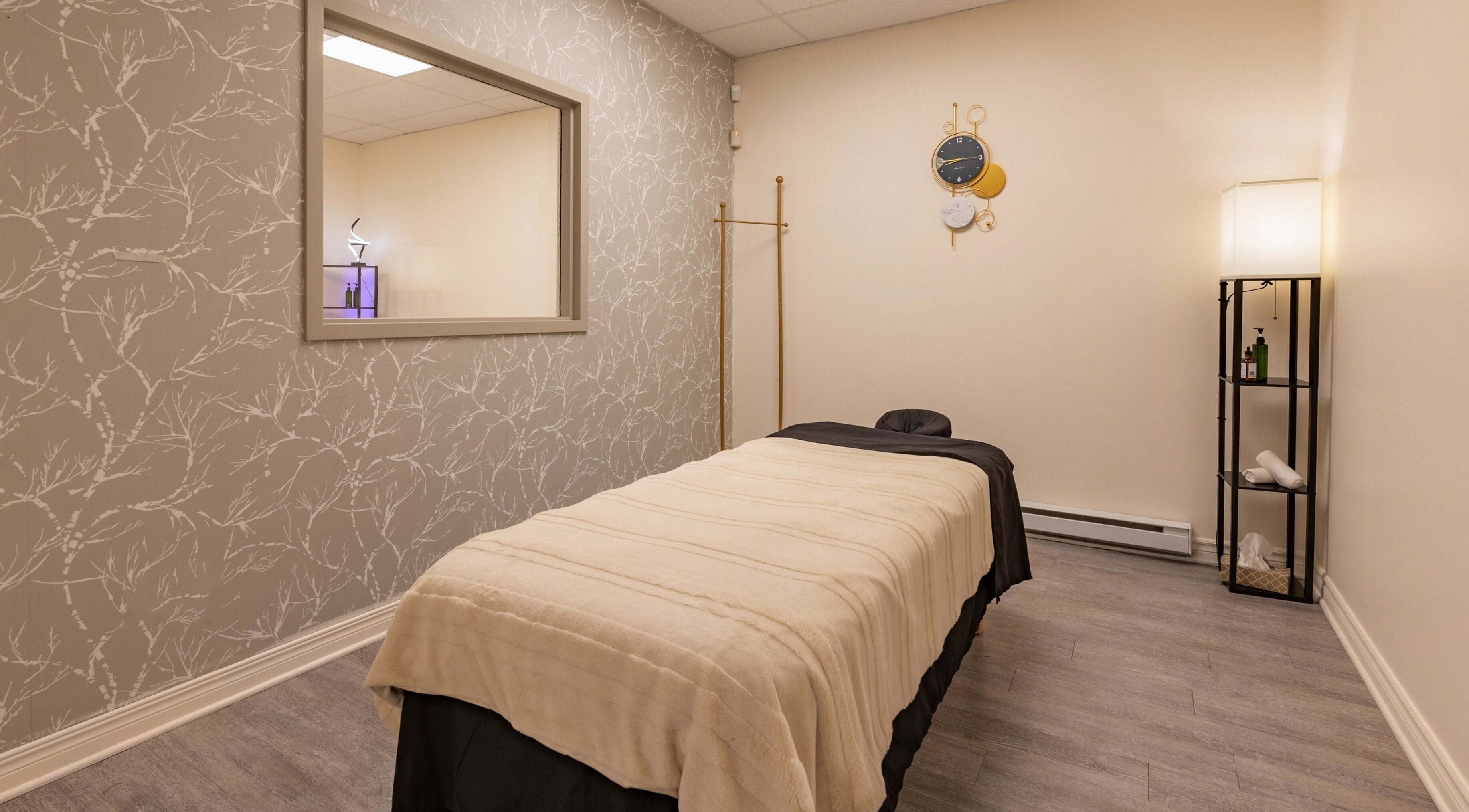 Relaxing massage room at Institut NewYou, Sainte-Anne-de-bellevue, Québec, CA with plush bed and elegant decor.