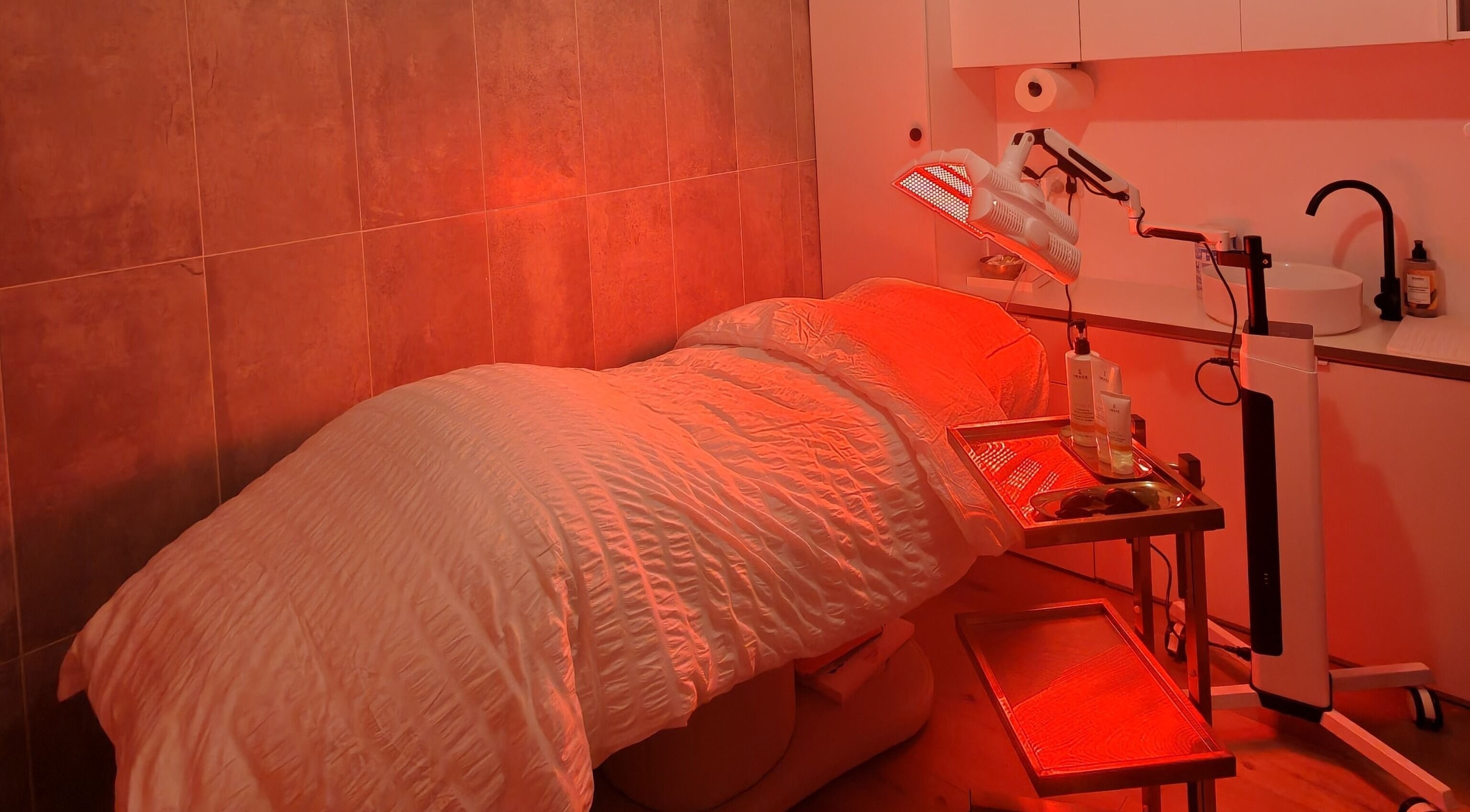 Tranquil treatment room at Asali Skin and Wellness in Malvern, South Australia, AU with a calming red light ambiance.