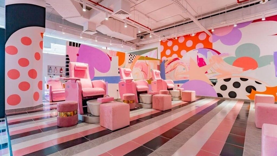 Vibrant nail salon at Pretty Wow, Dubai, Dubai, AE with pink chairs and artistic mural.