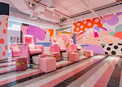 Vibrant nail salon at Pretty Wow, Dubai, Dubai, AE with pink chairs and artistic mural.