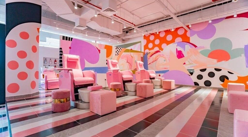 Vibrant nail salon at Pretty Wow, Dubai, Dubai, AE with pink chairs and artistic mural.