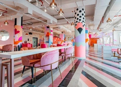 Bright, colorful interior of Pretty Wow, Dubai, Dubai, AE, featuring pink chairs and artistic decor.