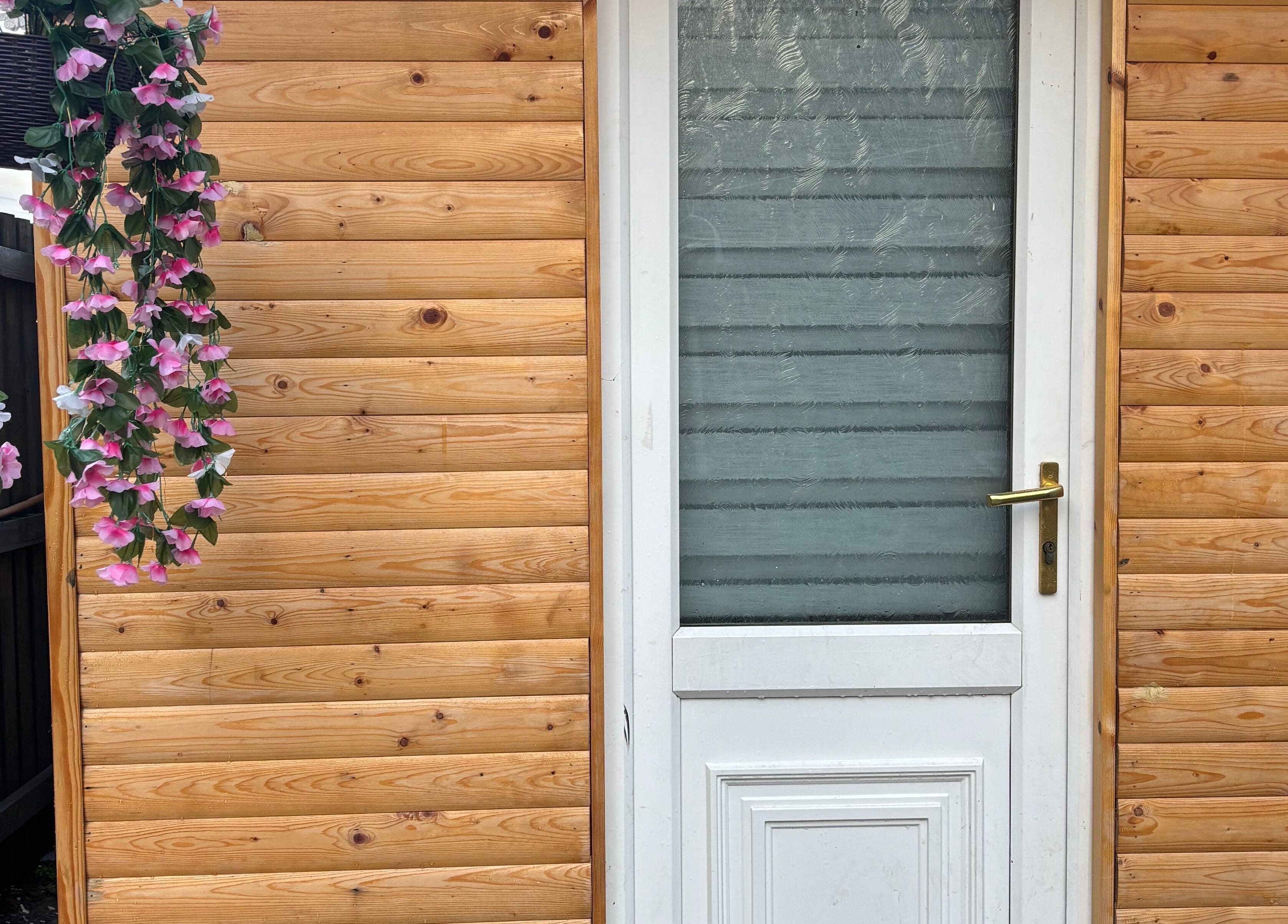 Charming wooden entrance with floral decor at Em Beauty Care, Airdrie, Scotland, GB.