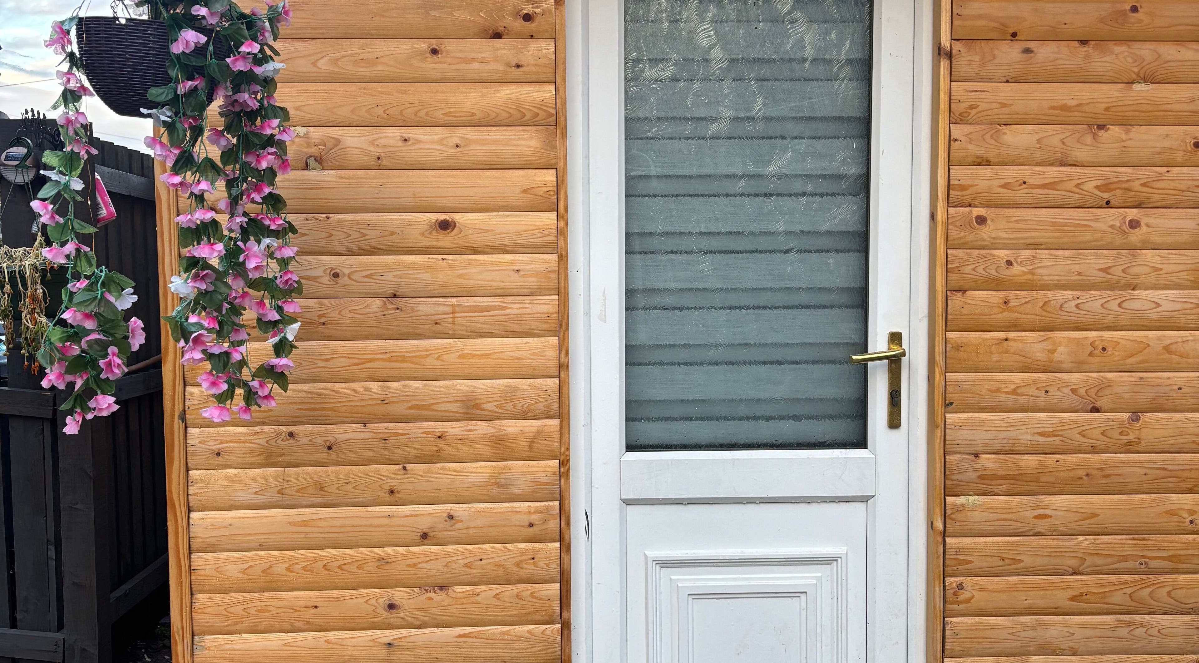 Charming wooden entrance with floral decor at Em Beauty Care, Airdrie, Scotland, GB.