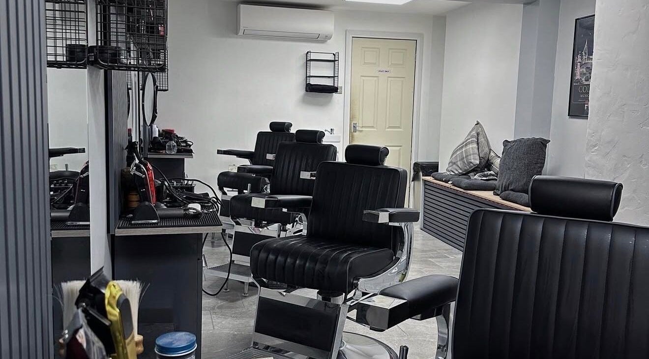Interior of The Doghouse Gentlemen's Barbers, Needham Market, England, showcasing black barber chairs and tools.