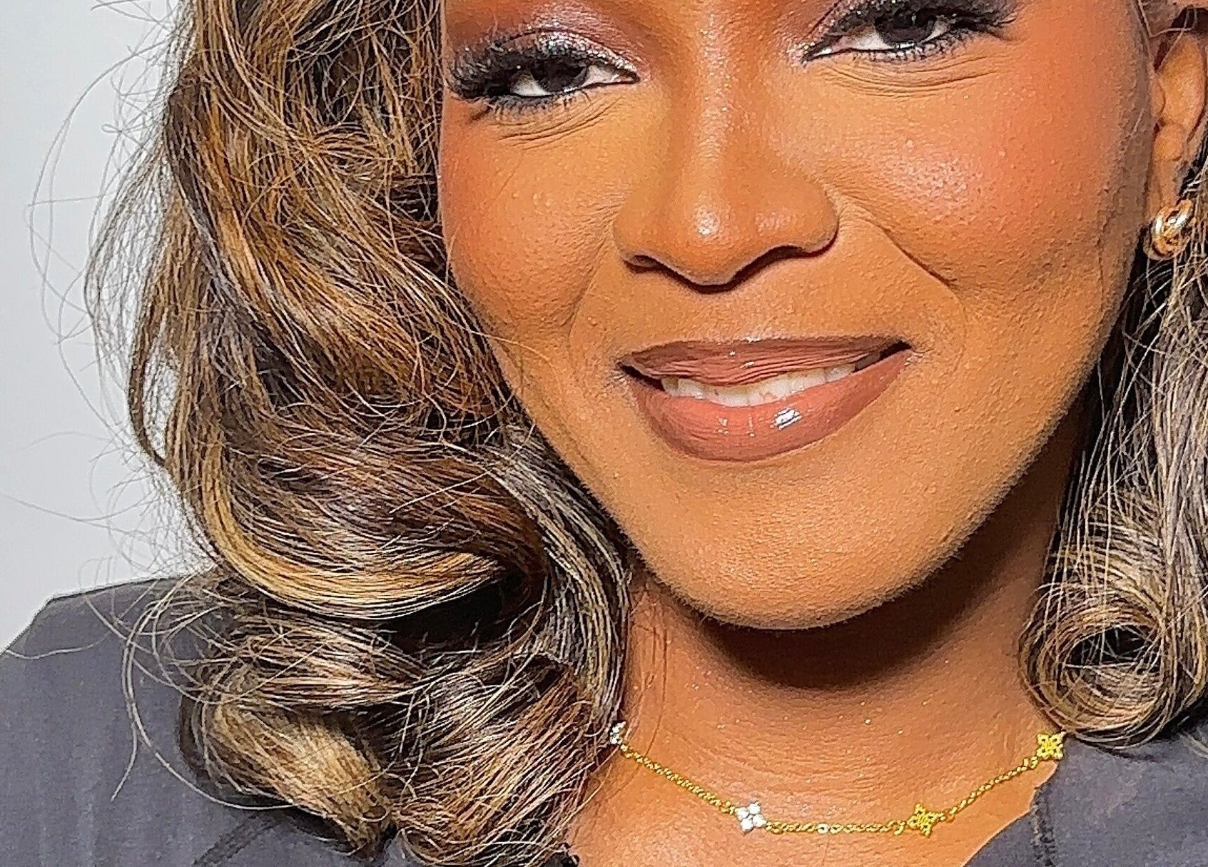 Woman smiling at Efoma’s Touch Artistry, Birmingham, England, GB, showcasing flawless makeup and hair.