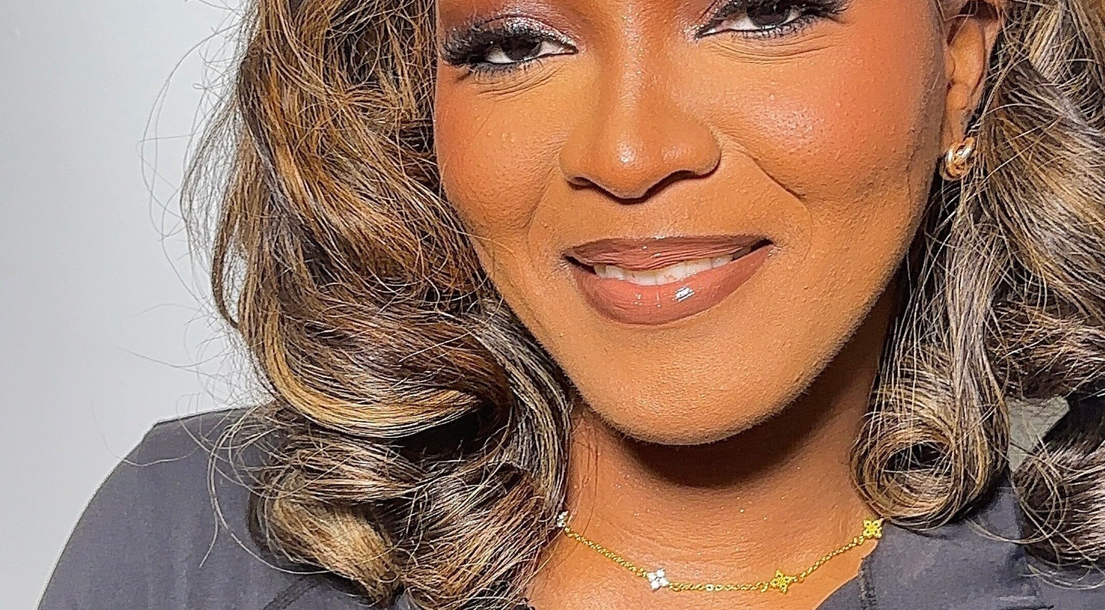 Woman smiling at Efoma’s Touch Artistry, Birmingham, England, GB, showcasing flawless makeup and hair.