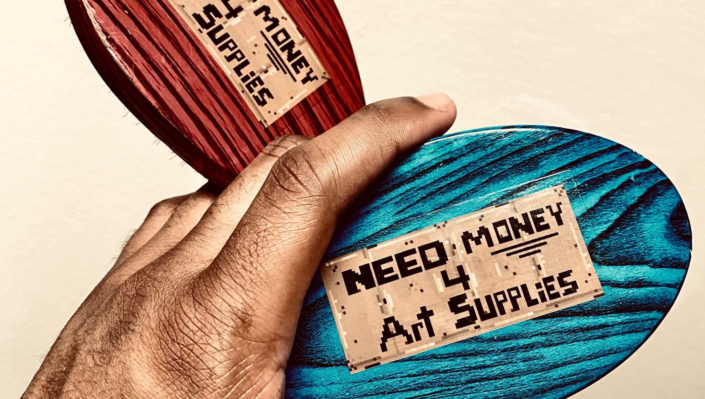 Creative design with 'Need Money 4 Art Supplies' held on colored wood at BONE | BARBER + SMP, Spring, Texas, US.