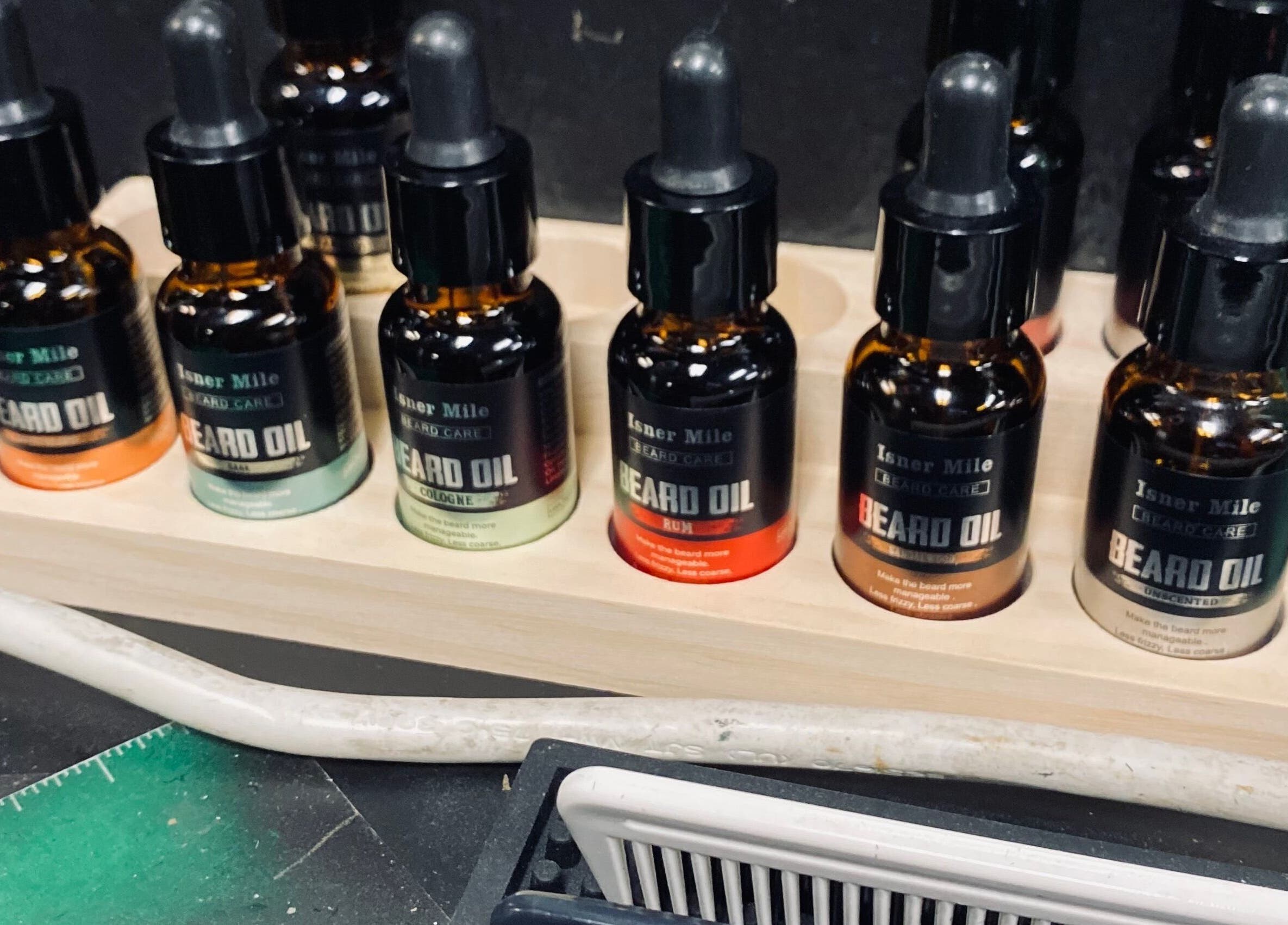 BONE | BARBER + SMP in Spring, Texas, US showcases a selection of premium beard oils on a wooden stand.