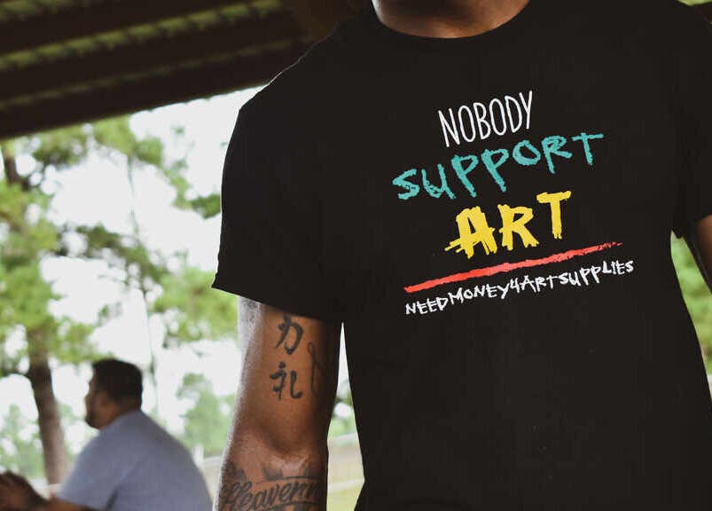 Tattooed individual with artistic T-shirt at BONE | BARBER + SMP in Spring, Texas, US.