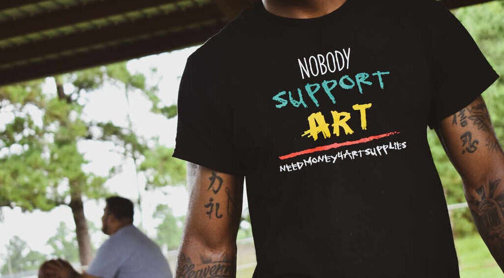 Tattooed individual with artistic T-shirt at BONE | BARBER + SMP in Spring, Texas, US.