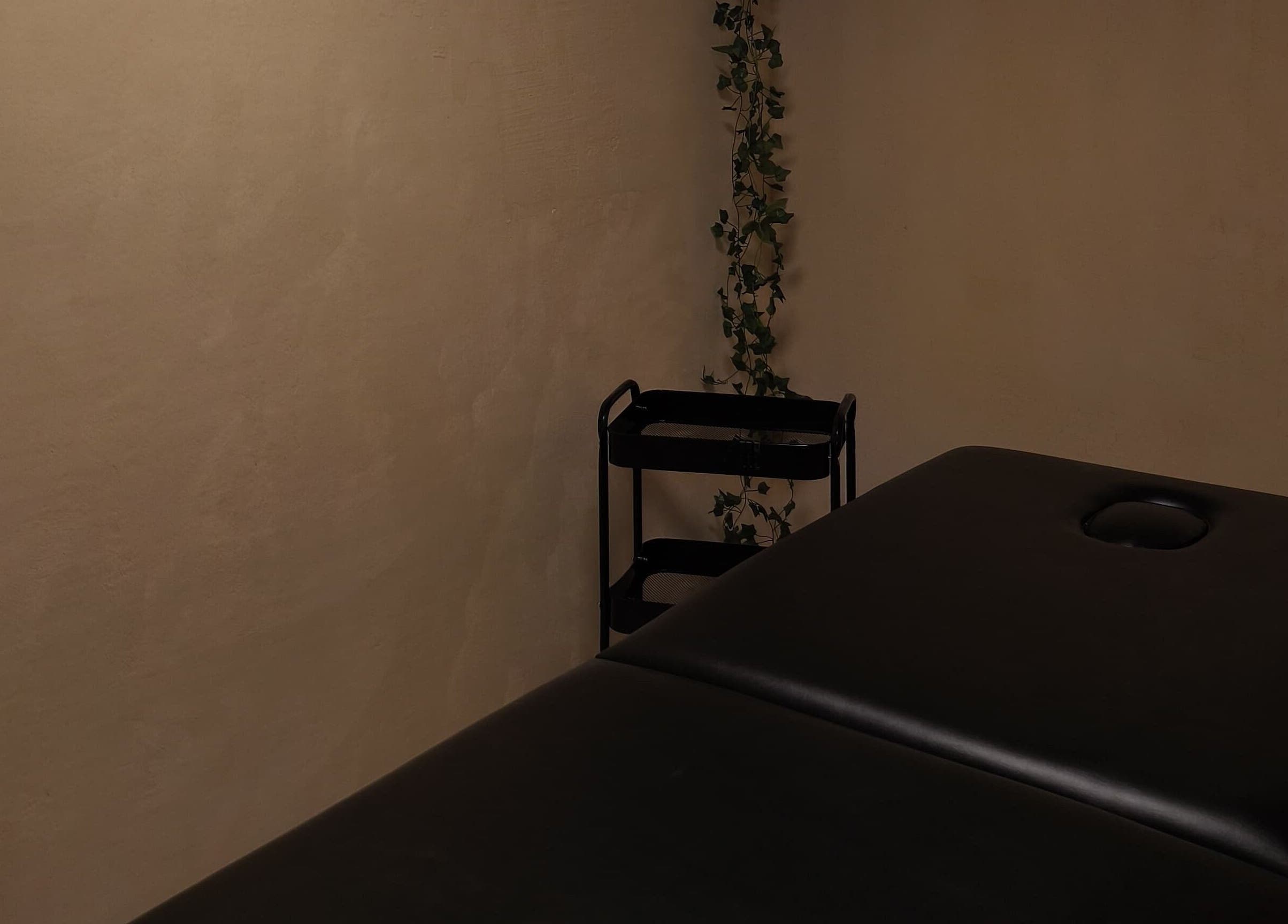 Sala de masaje en Aurea Bienestar Integral, Ciudad De México, MX, con camilla negra y decoración minimalista.