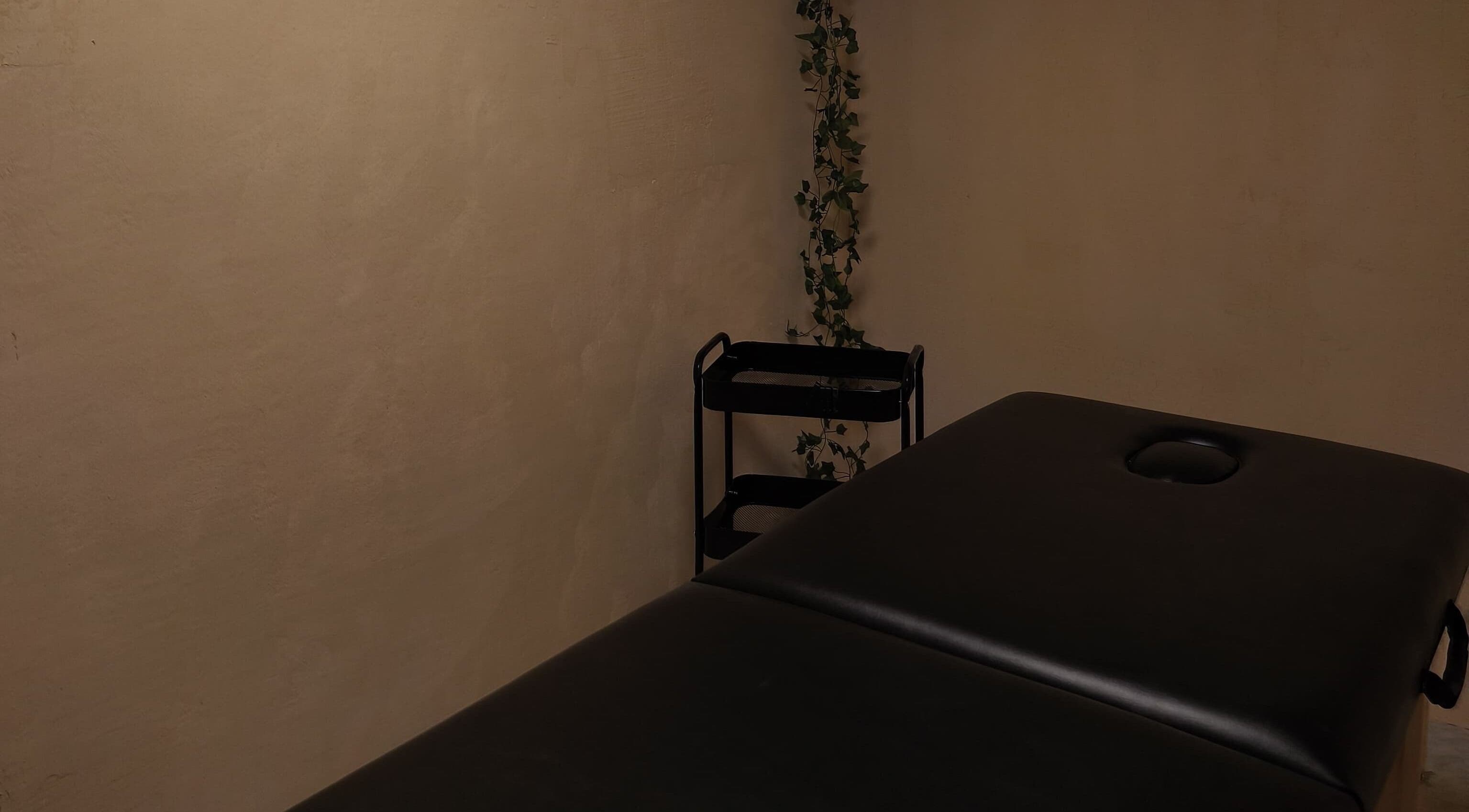 Sala de masaje en Aurea Bienestar Integral, Ciudad De México, MX, con camilla negra y decoración minimalista.