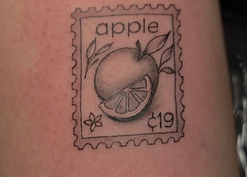 Apple stamp tattoo at Lumie Aure Beauty Studio in Ottawa, Ontario, CA. Unique body art design.
