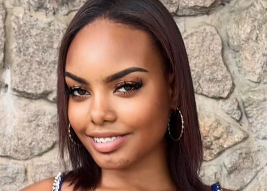Person smiling against a stone wall at Le Studio De Malik in Paramaribo, Paramaribo, SR.