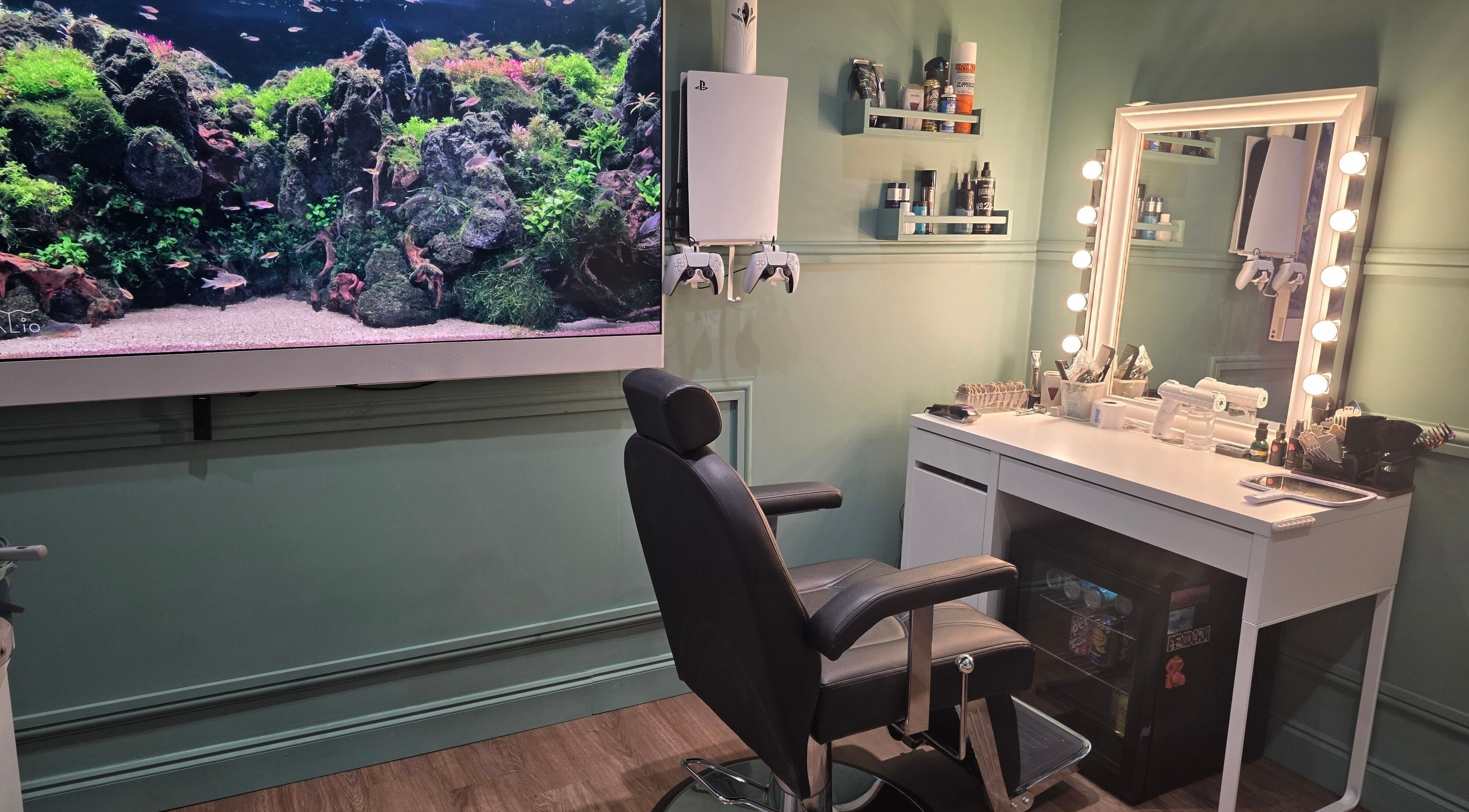 Modern barber station with illuminated mirror and fish tank at The Green Room Barbers, Leeds, England, GB.