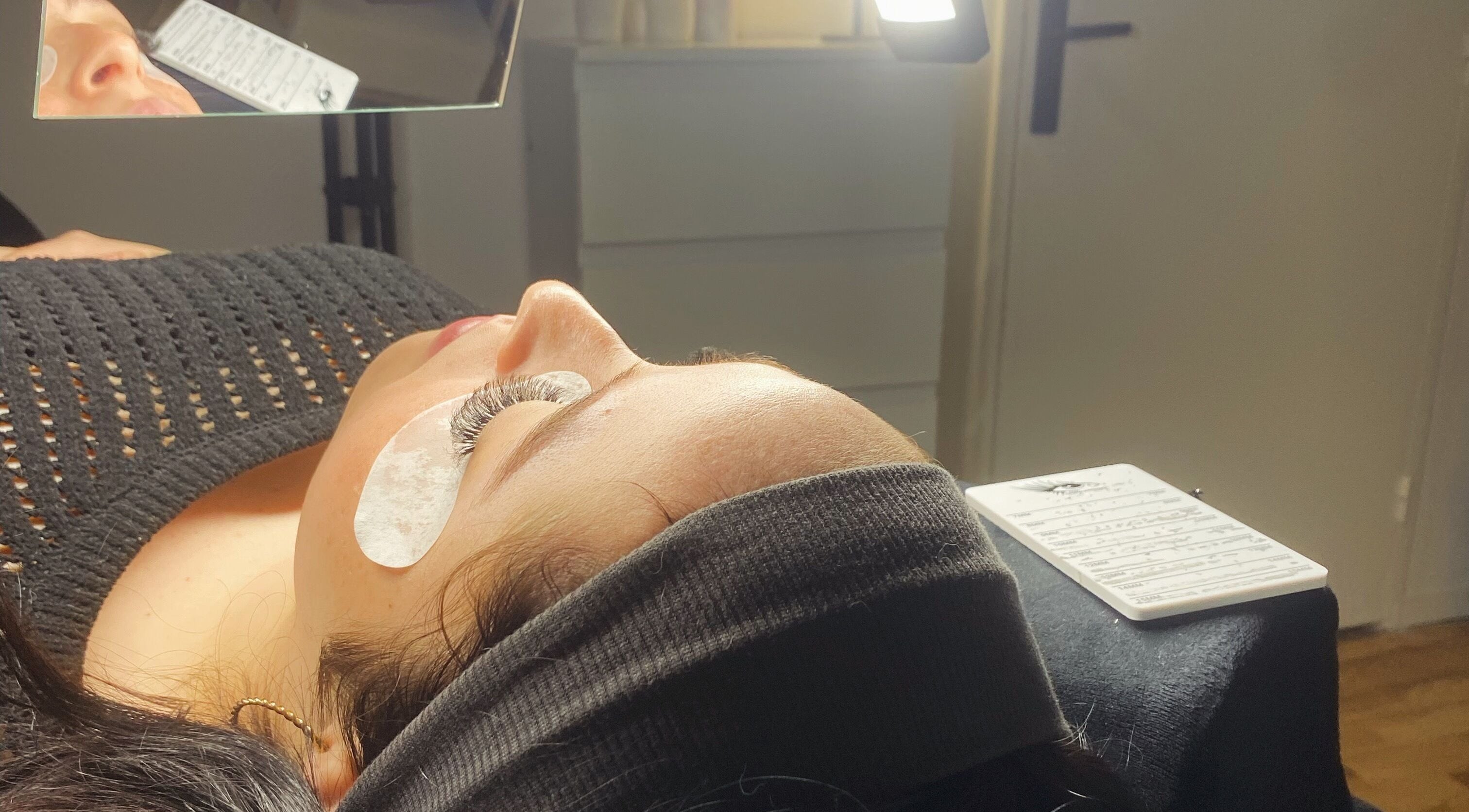 Extension de cils à Mya Beauty, Ostwald, Grand Est, FR. Femme allongée avec des patchs sous les yeux.