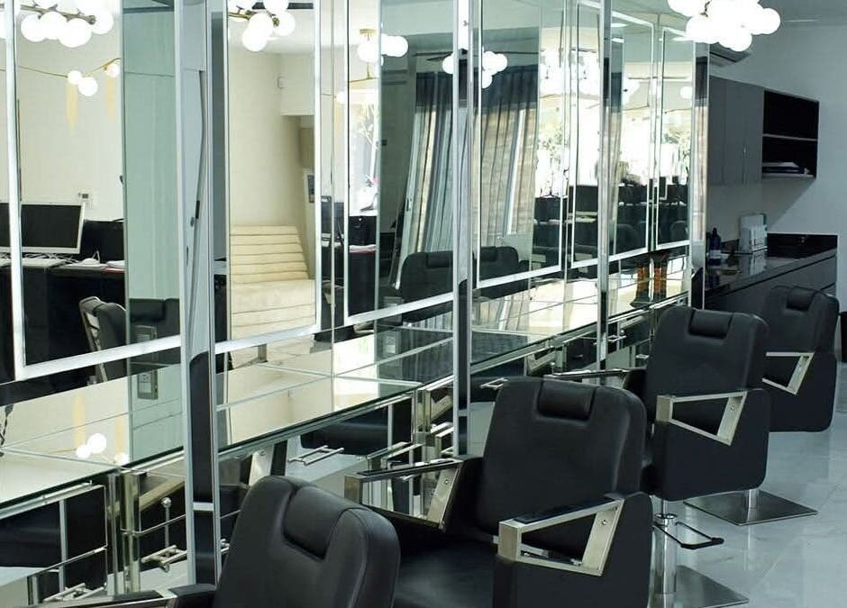 Área de peluquería elegante en Jesús Luna @GlamHouse, Puerto Vallarta, MX, con sillas modernas y espejos amplios.