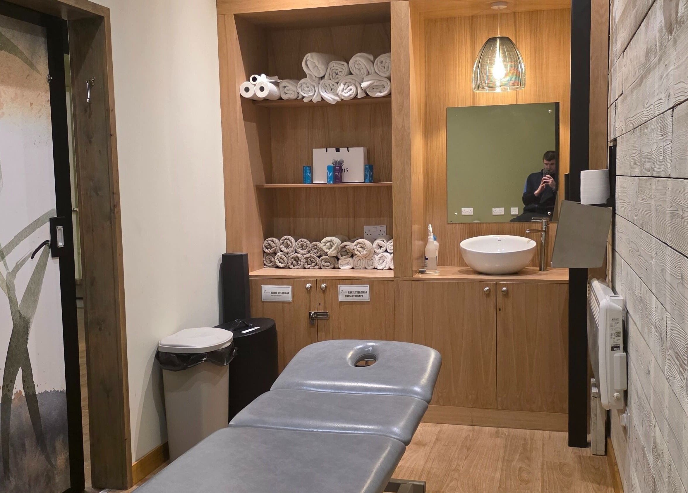 Calm therapy room at Kineticflowtherapy, Preston, England, GB, featuring a massage table and wooden shelves.