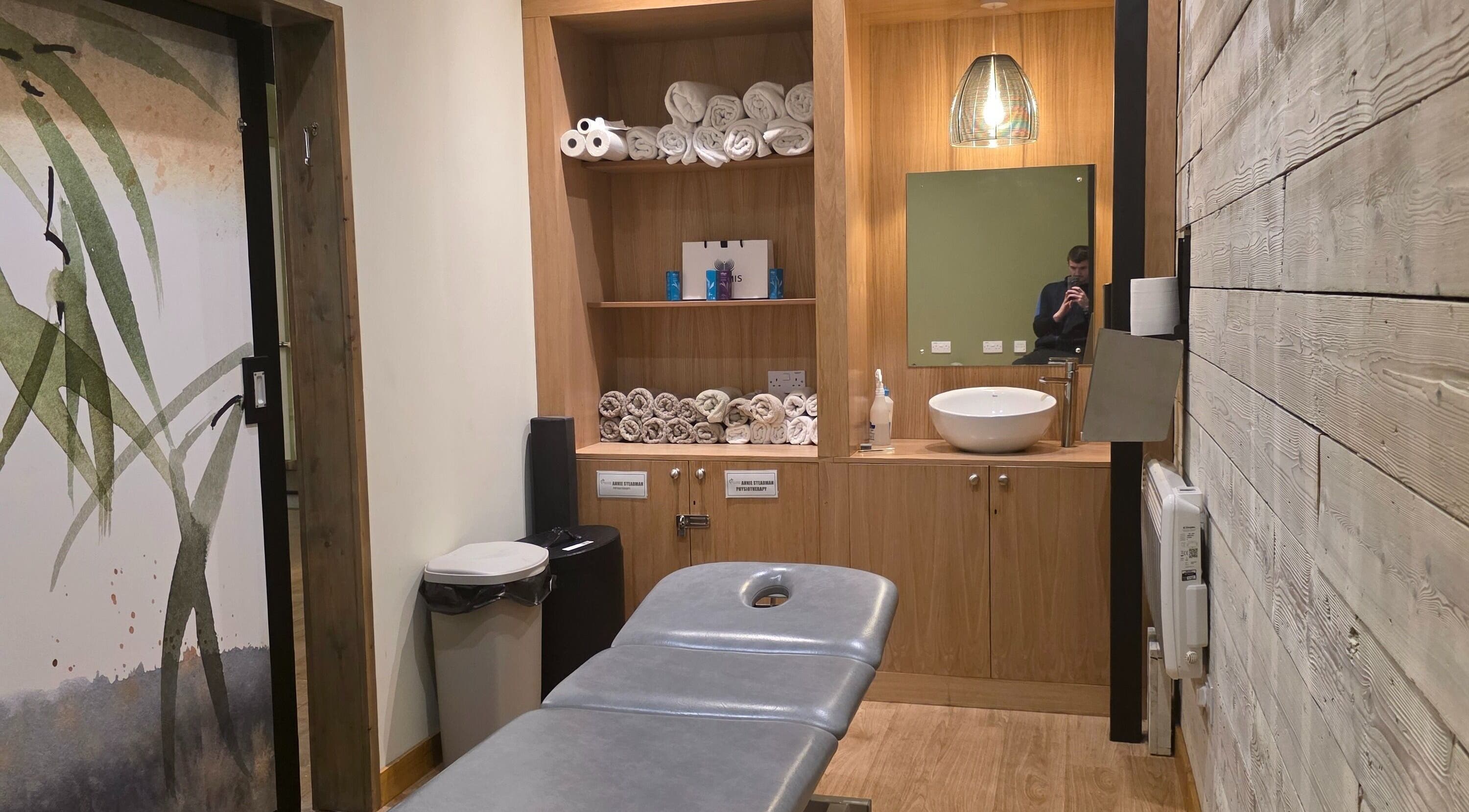 Calm therapy room at Kineticflowtherapy, Preston, England, GB, featuring a massage table and wooden shelves.