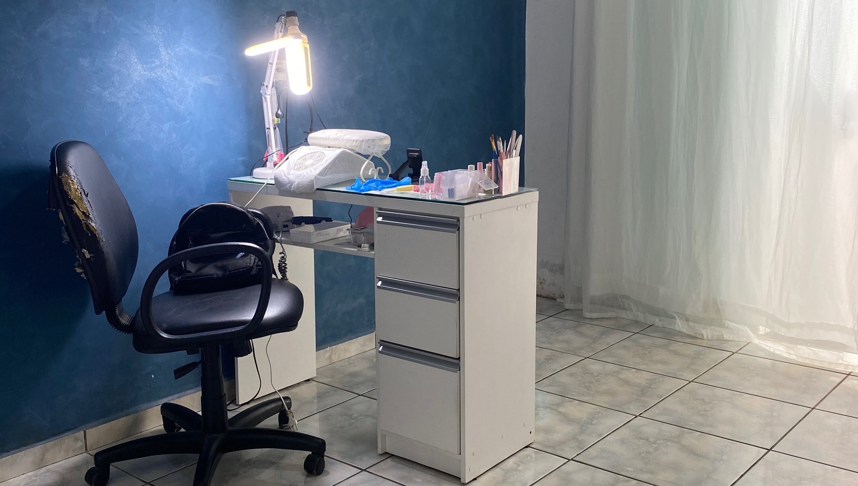 Estação de trabalho na Lucia Correia Nail Design, Paraná, PR, BR, com cadeira e mesa organizada.