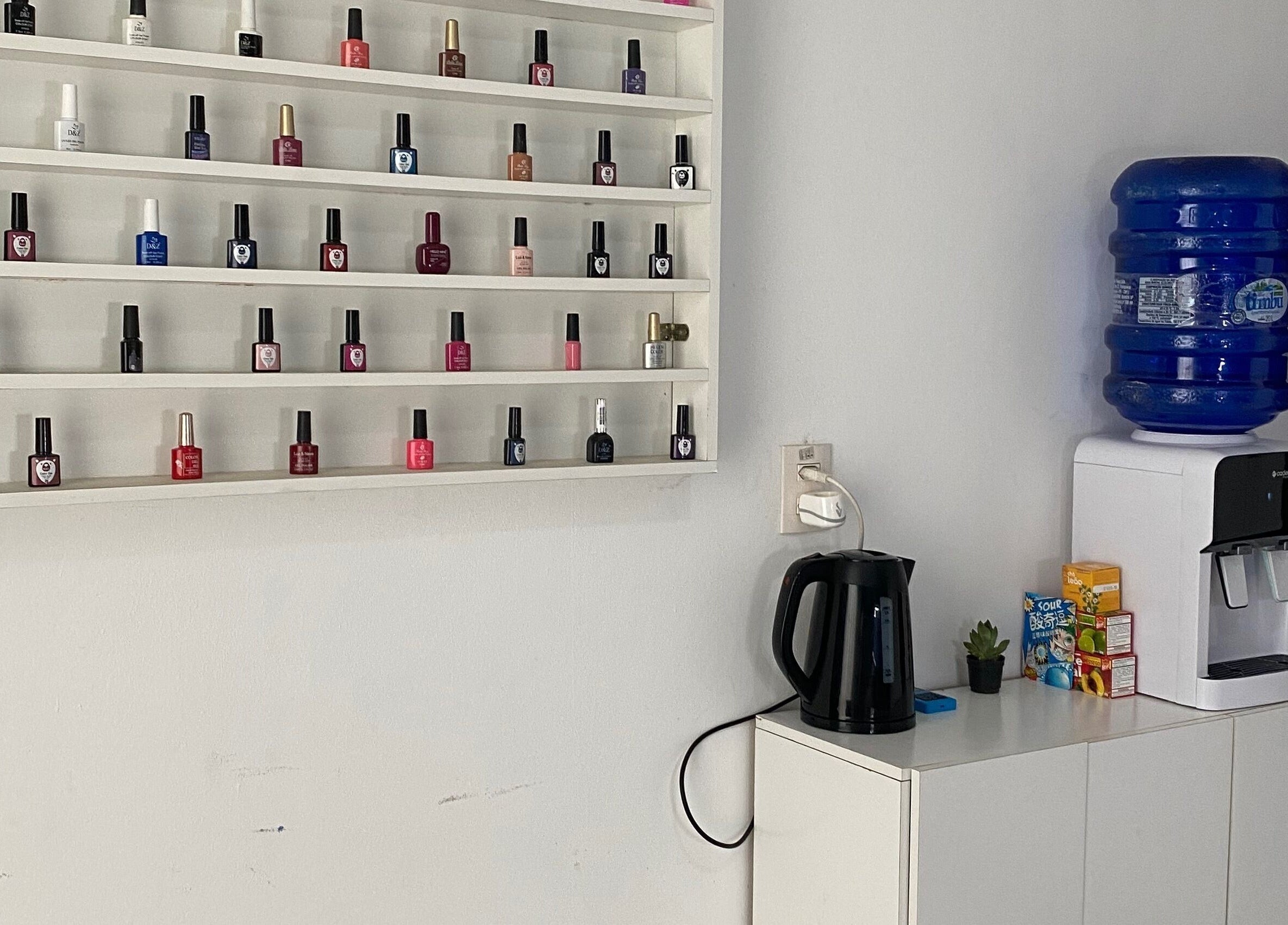 Prateleira de esmaltes na Lucia Correia Nail Design, Paraná, Paraná, BR, com dispensador de água.