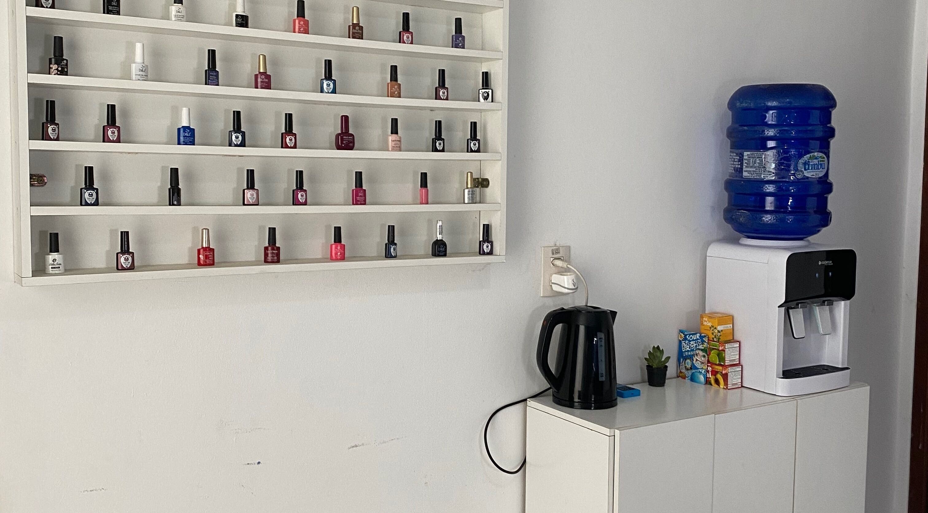 Prateleira de esmaltes na Lucia Correia Nail Design, Paraná, Paraná, BR, com dispensador de água.