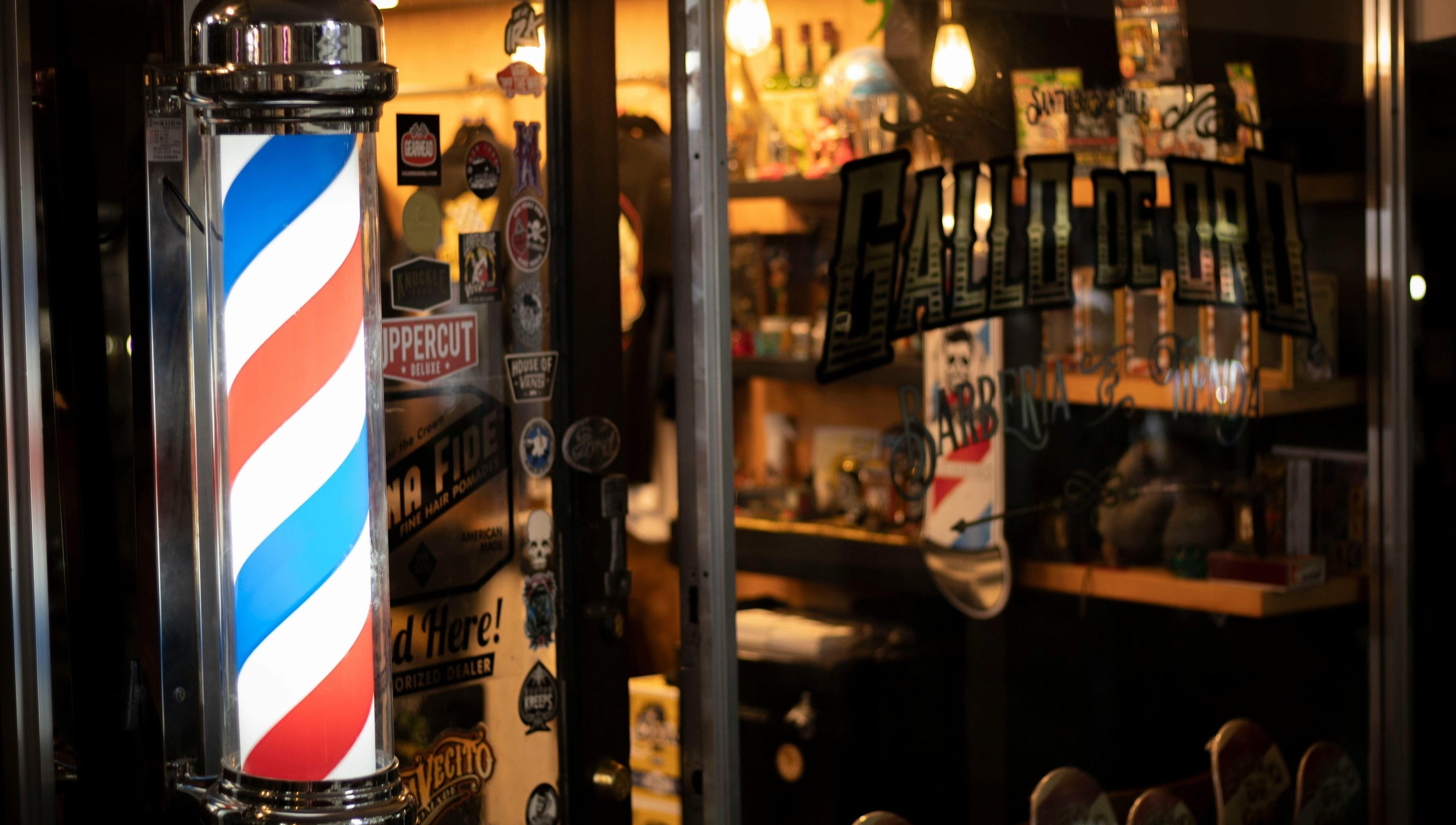 Entrada iluminada de BarberyandBeauty CR en Aserri, San José, con poste de barbería clásico.