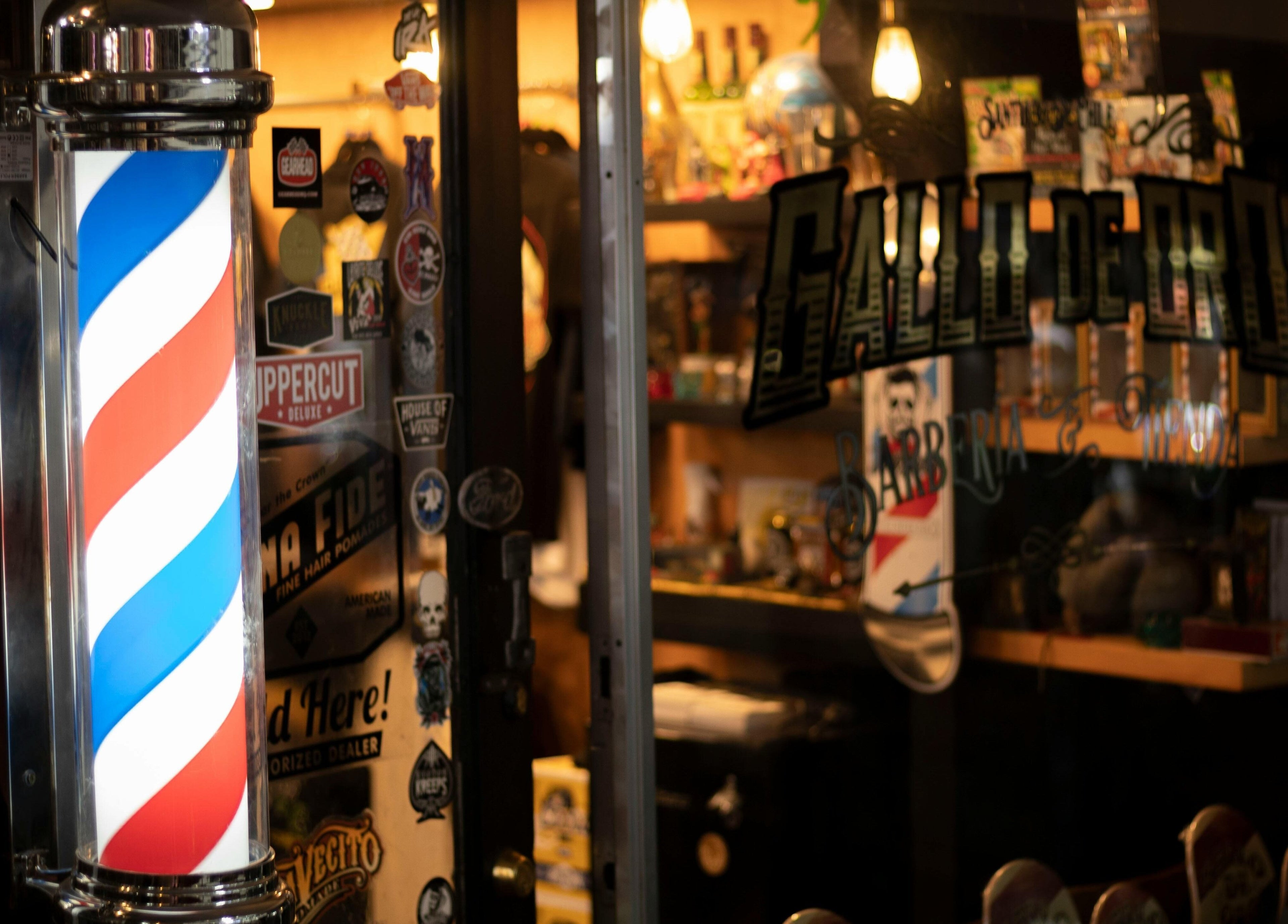 Entrada iluminada de BarberyandBeauty CR en Aserri, San José, con poste de barbería clásico.