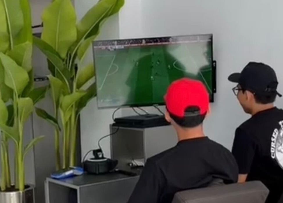 Relaxing lounge area at Human Barber Club Vol 2 in Bali, ID with patrons enjoying a game on TV.