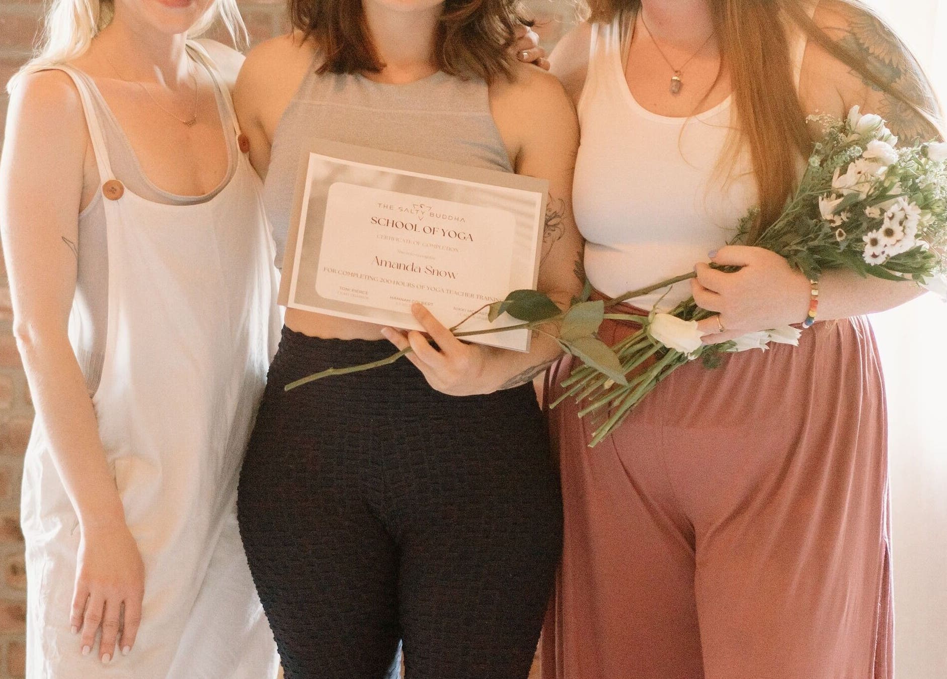 Graduates holding yoga certificates at Ethereal Path Wellness in Brookline, Massachusetts, US, celebrating success.