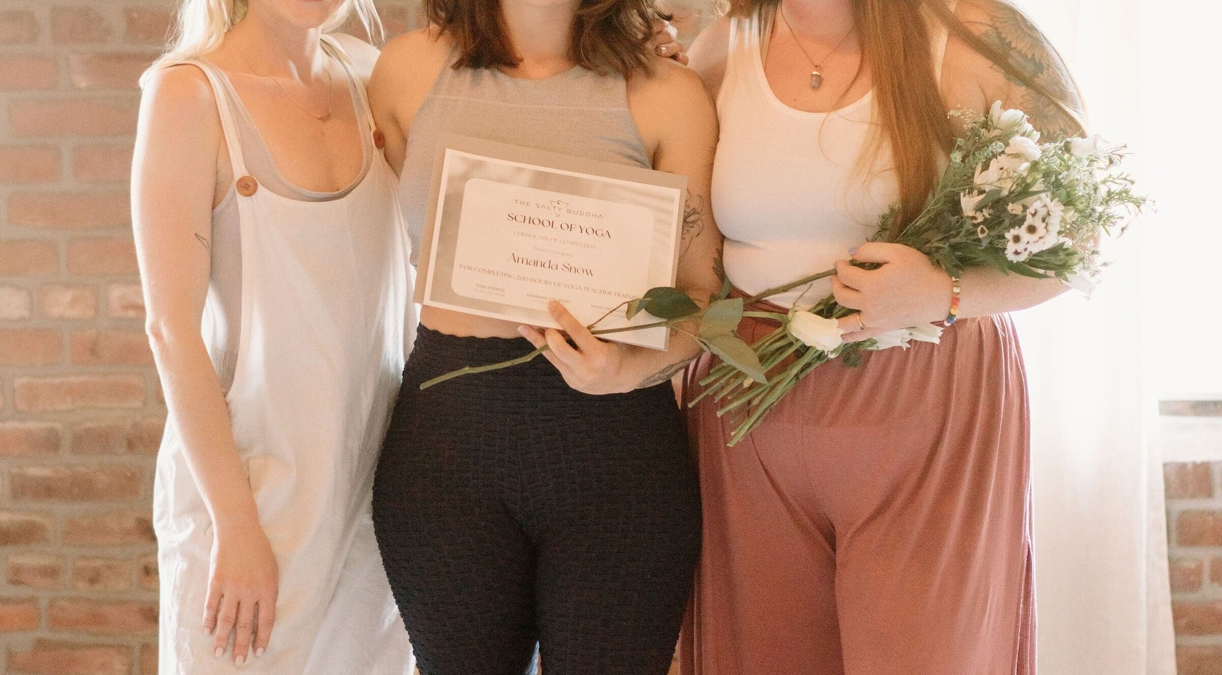 Graduates holding yoga certificates at Ethereal Path Wellness in Brookline, Massachusetts, US, celebrating success.