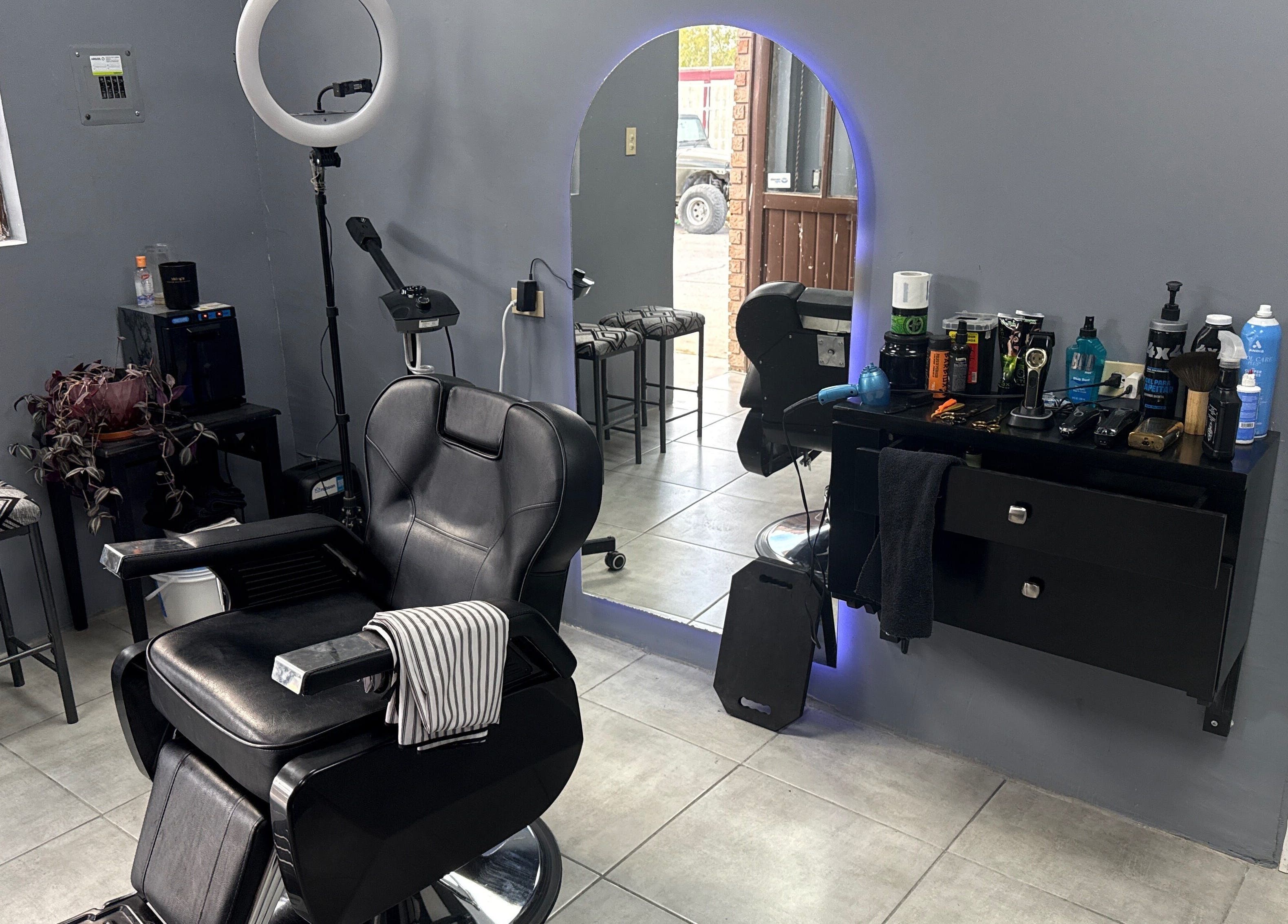 Interior moderno de Mucho Pelo Barber Studio en Juárez, Chihuahua, MX con espejos iluminados y sillas elegantes.