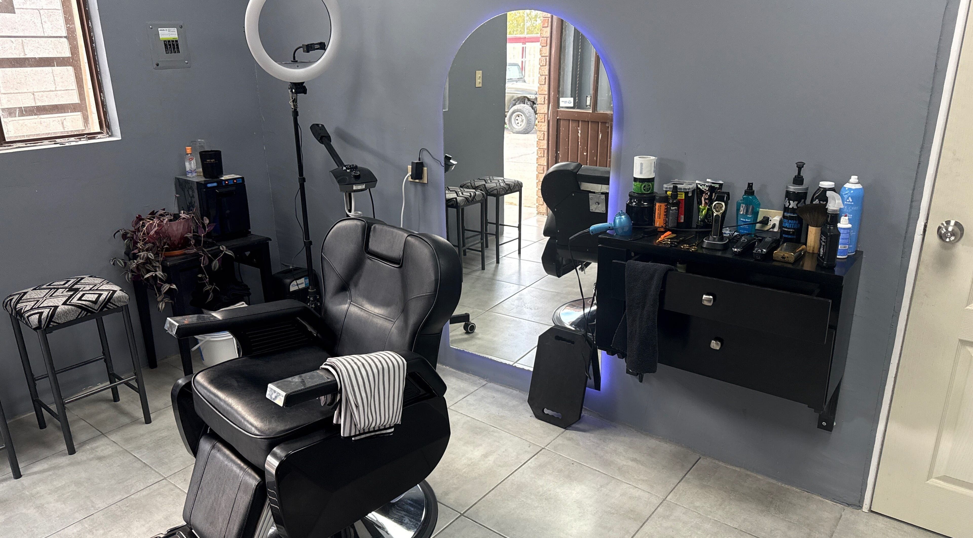 Interior moderno de Mucho Pelo Barber Studio en Juárez, Chihuahua, MX con espejos iluminados y sillas elegantes.