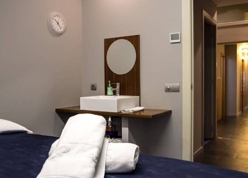 Habitación de masajes en Benessia & Benestar, Barcelona, Catalunya, ES, con cama y lavabo moderno.